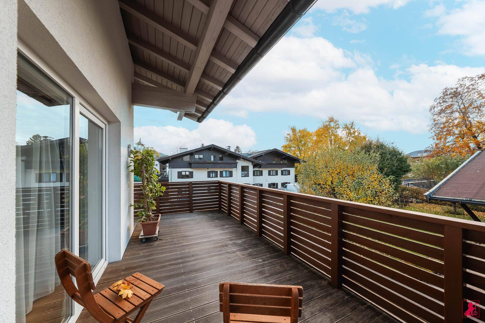 Großer Balkon mit Holzboden und Sitzgelegenheiten, ideal zum Entspannen mit Blick auf die herbstliche Umgebung.