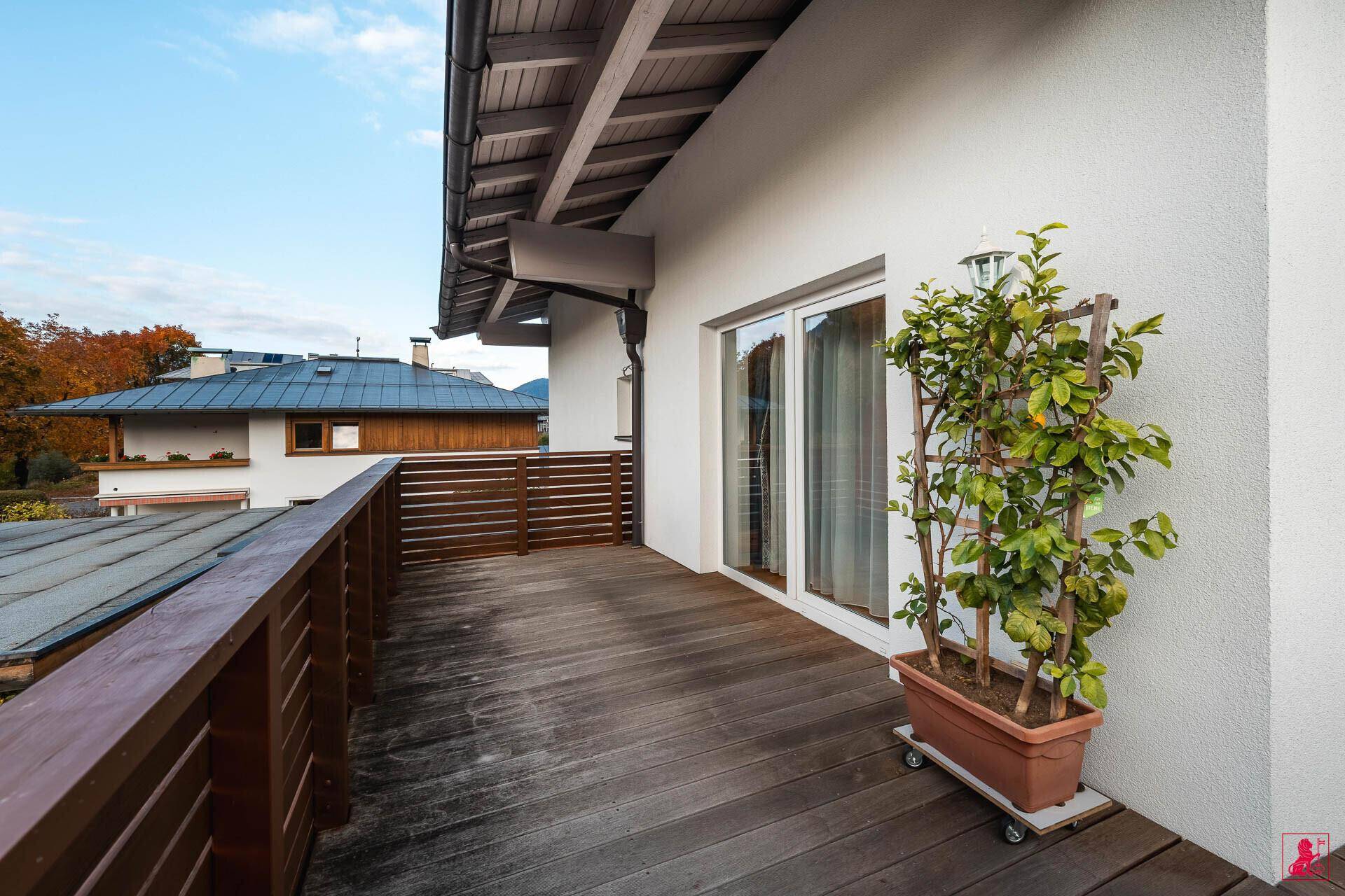 Heller Balkon mit Holzboden und Pflanzen, bietet einen ruhigen Außenbereich mit Blick auf die Nachbarschaft.