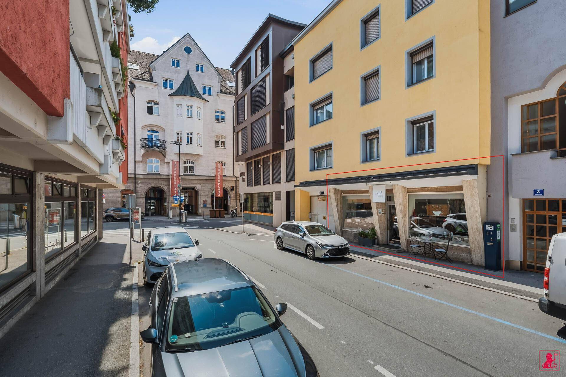 Außenansicht des Geschäftsgebäudes an einer belebten Straße mit parkenden Autos.