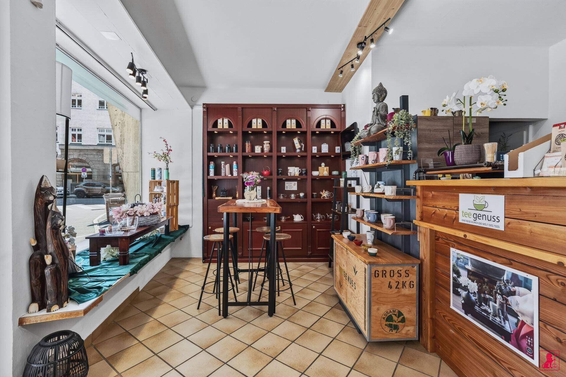 Heller Innenraum eines Teegeschäfts mit großem Schaufenster, Holztresen und Regalen.