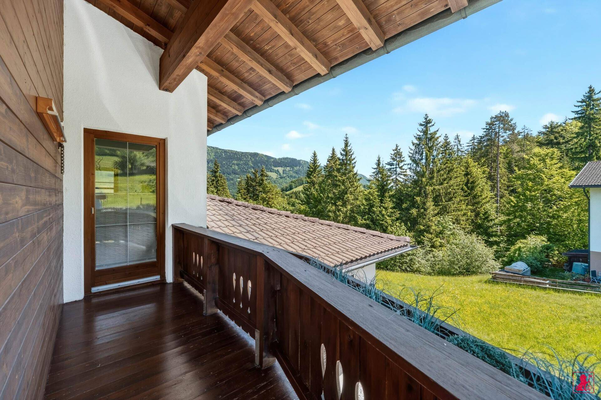 Balkon mit Holzboden und Geländer, bietet weite Aussicht auf die Natur.