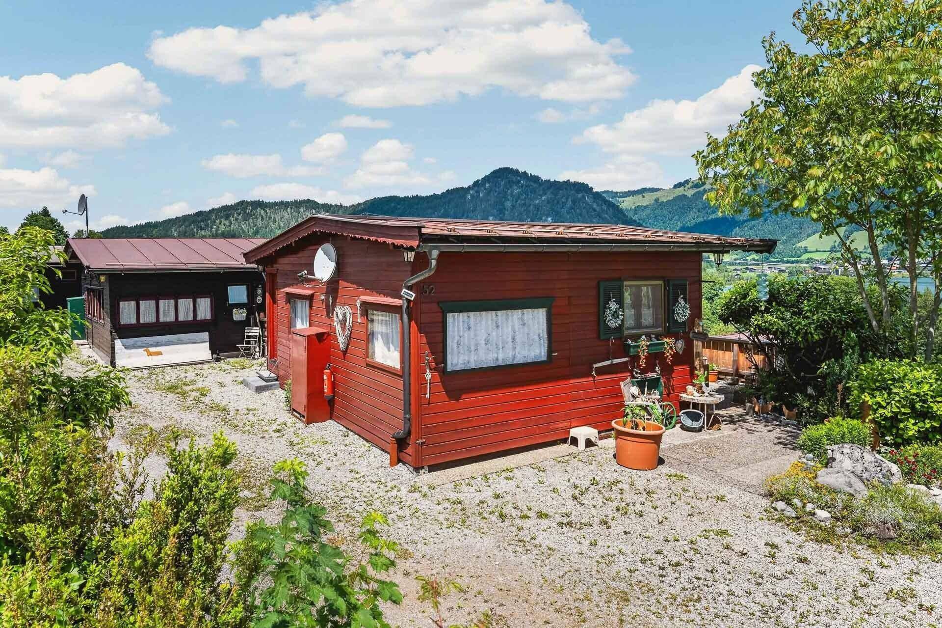 Charmantes rotes Holzhaus in ländlicher Umgebung mit Blick auf die Berge und den See.