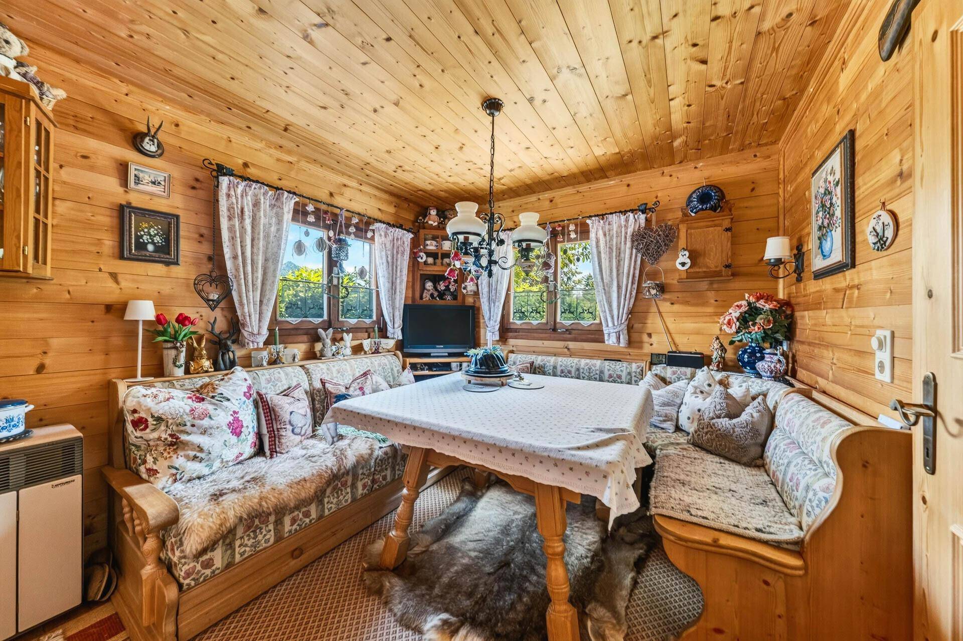 Gemütlicher Wohnbereich mit Holztäfelung, Esstisch und traditionellen Sitzbänken im Landhausstil.