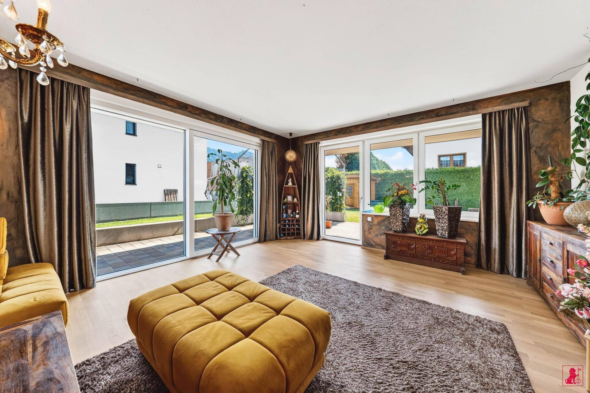 Geräumiges Wohnzimmer mit großen Fenstern, Holzboden und Zugang zur Terrasse.