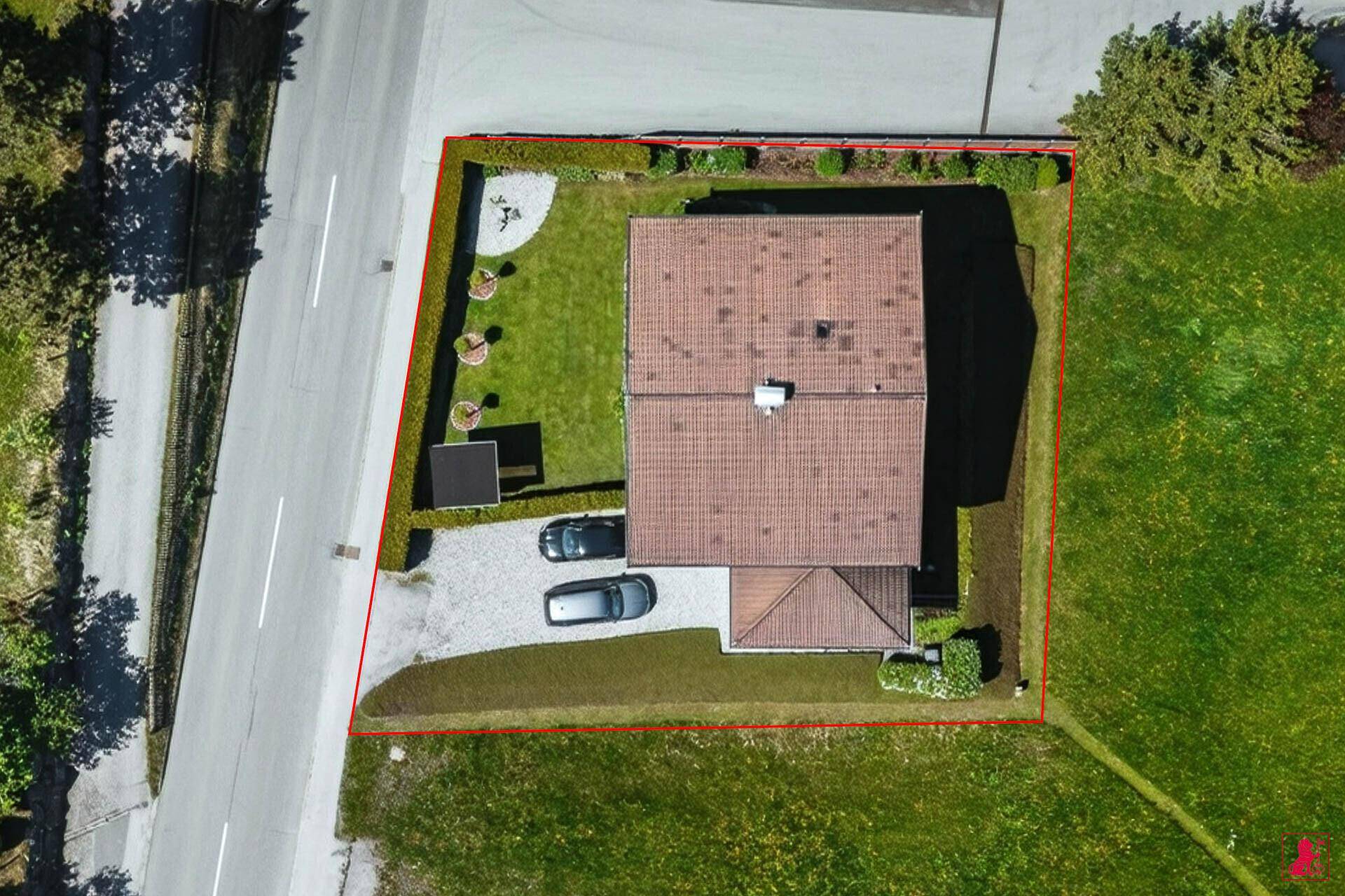 Luftaufnahme eines Einfamilienhauses mit Satteldach, Garten, Zufahrt und umzäuntem Grundstück.