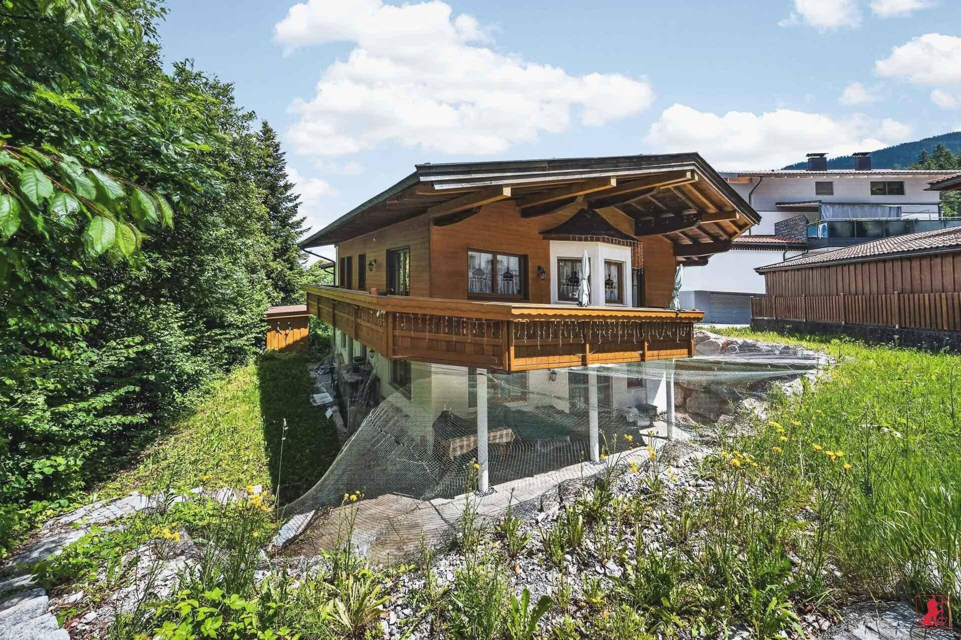 Ansicht des Holzhauses mit seiner Architektur und der umliegenden grünen Natur.