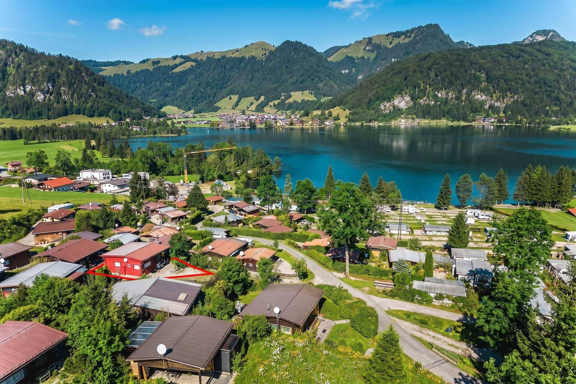 Detaillierte Luftaufnahme der Siedlung am Seeufer mit Bergpanorama im Hintergrund.