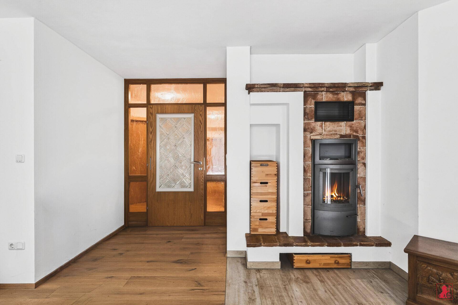 Eingangsbereich mit einem traditionellen Holzofen und Holzboden, der eine warme Atmosphäre schafft.
