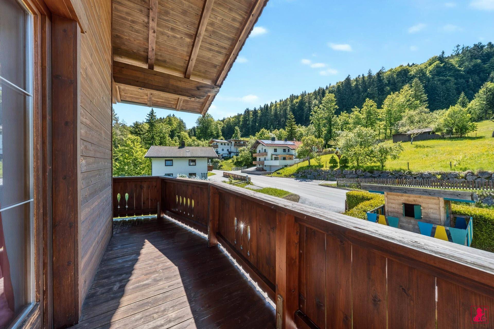 Geräumiger Holzbalkon mit Blick auf die umliegende Landschaft und Berge.