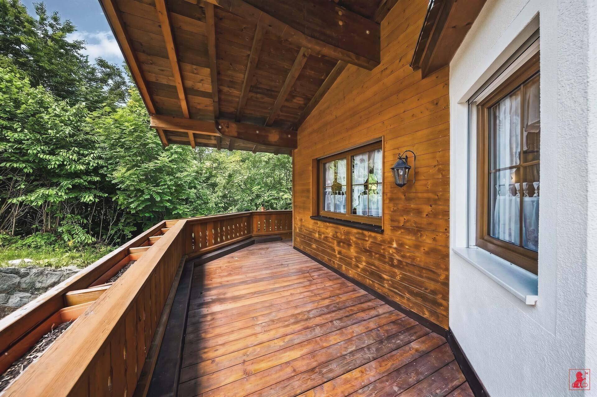 Langer Holzbalkon mit Holzfassade und Blick auf die umliegende Natur.
