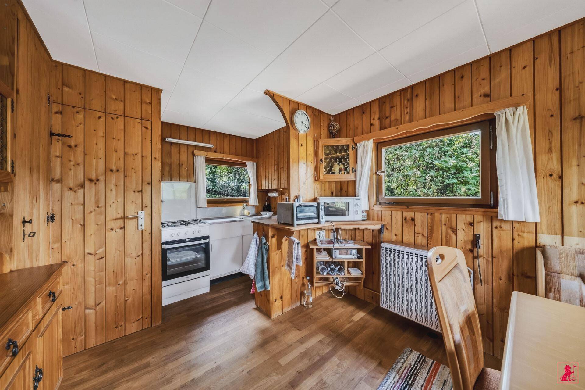 Kleine Küchenzeile im offenen Wohnbereich mit Holzvertäfelung und Fenster.