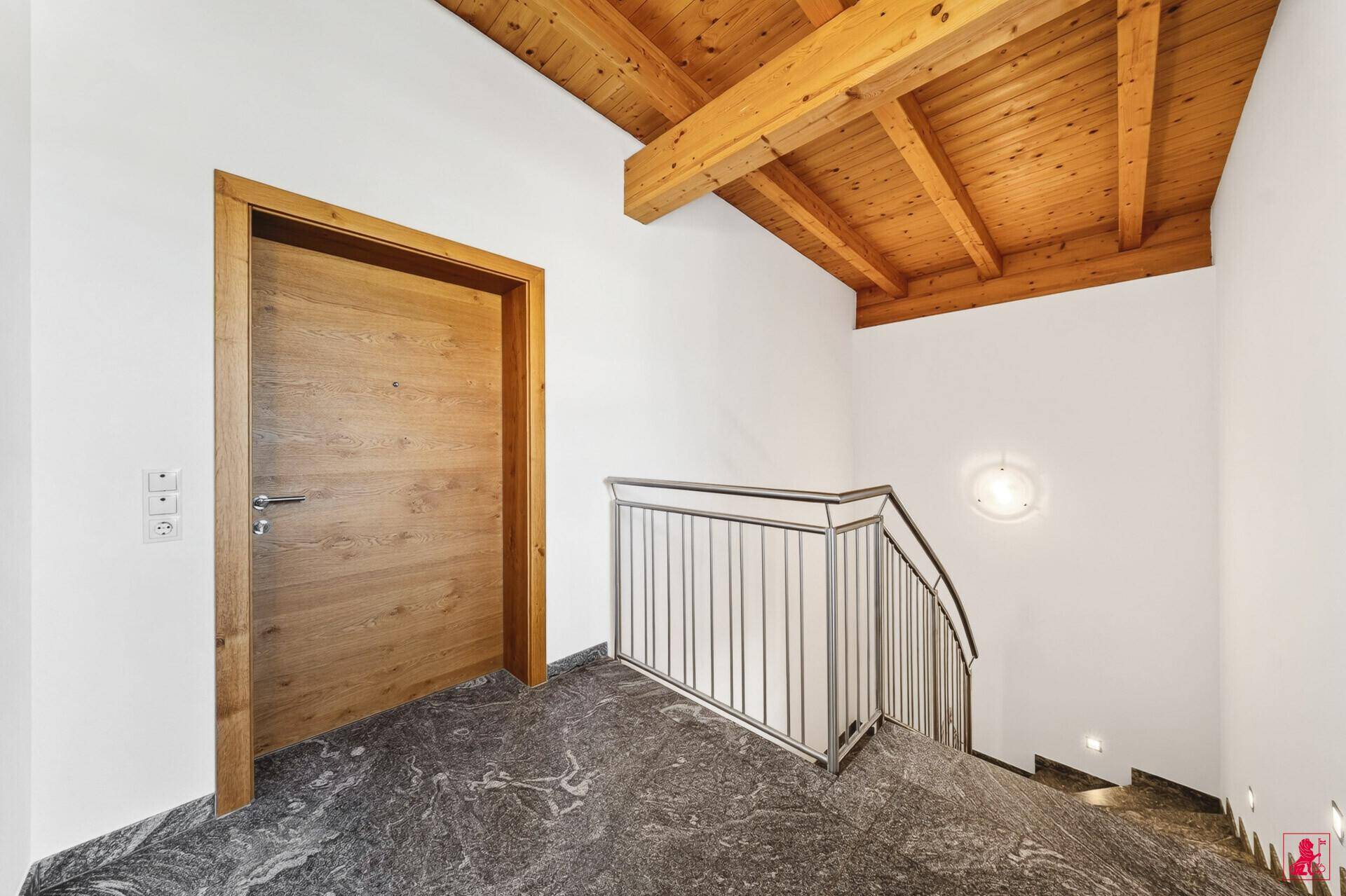 Eingangsbereich mit Holzdecke, Steinfliesen und Treppe zum Obergeschoss.
