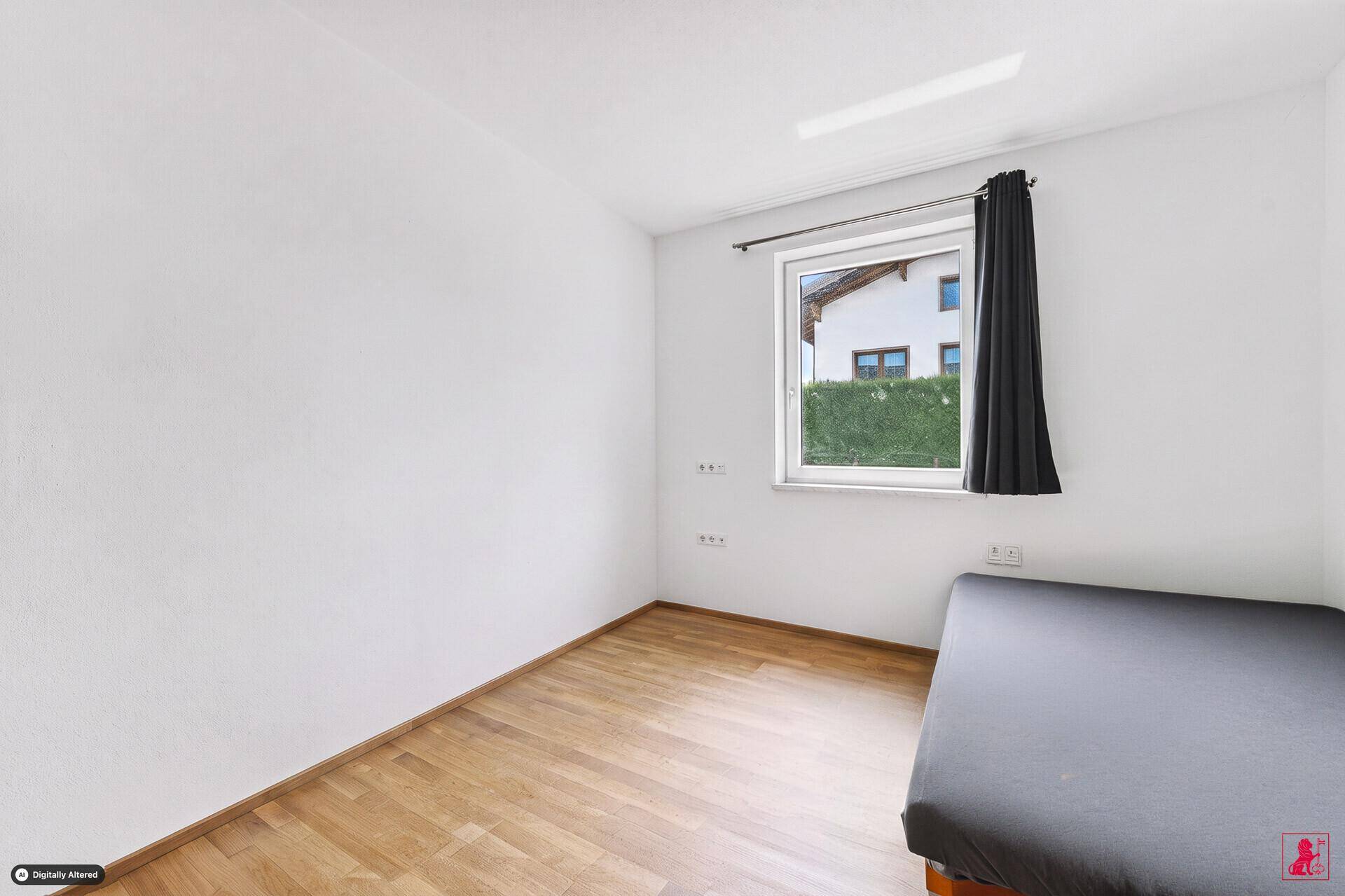 Einfaches Schlafzimmer mit Holzboden und Fenster mit Blick ins Grüne.