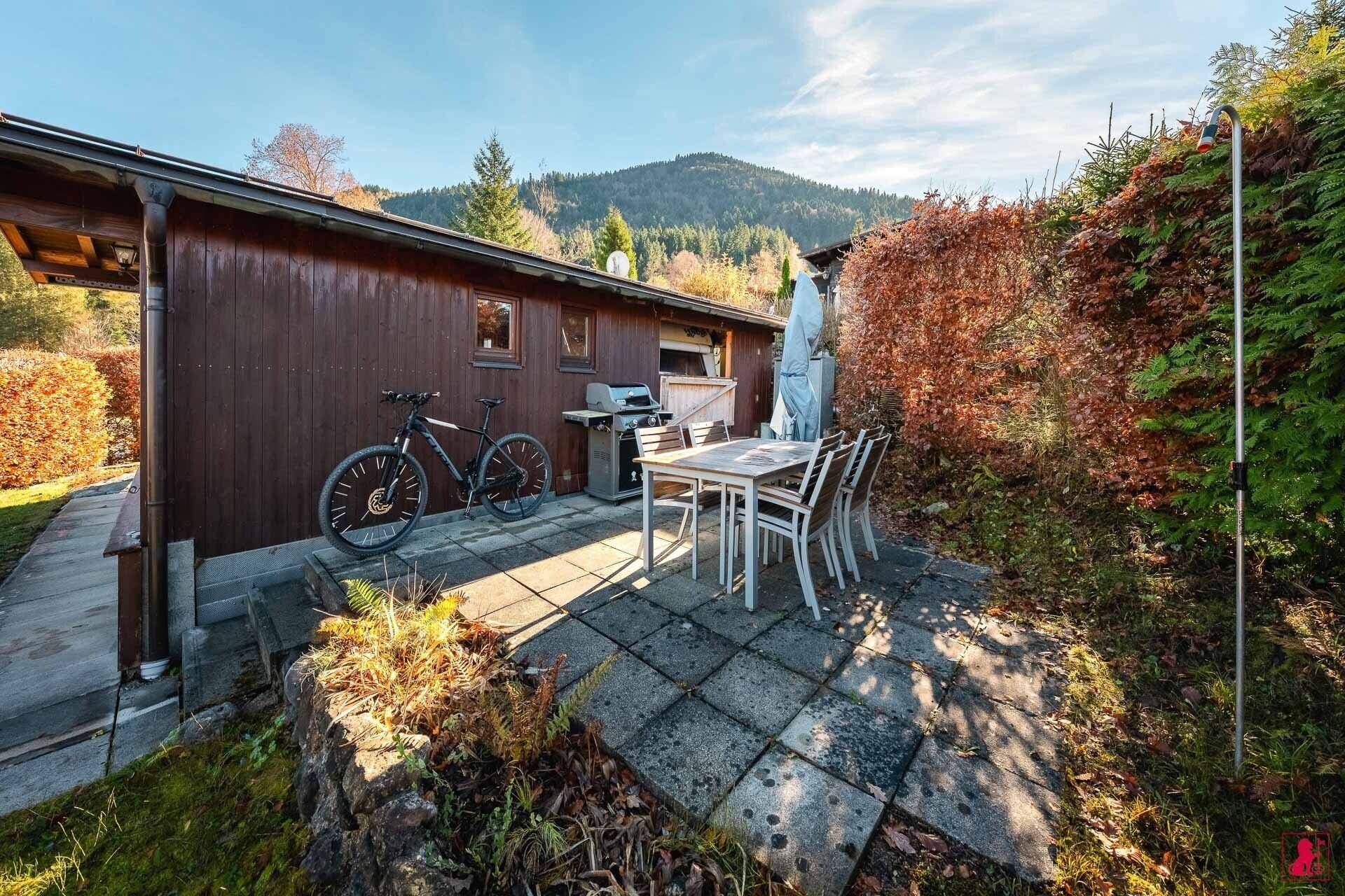 Geräumige Terrasse mit Esstisch, Grillbereich und Blick auf die umliegende Natur.