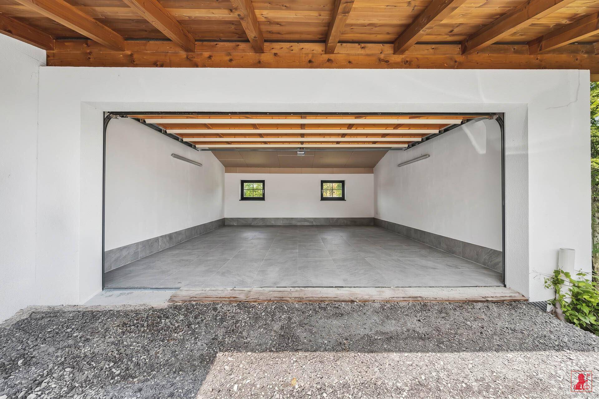 Geräumige, leere Garage mit Betonboden und sichtbaren Holzdeckenbalken, bietet viel Platz.