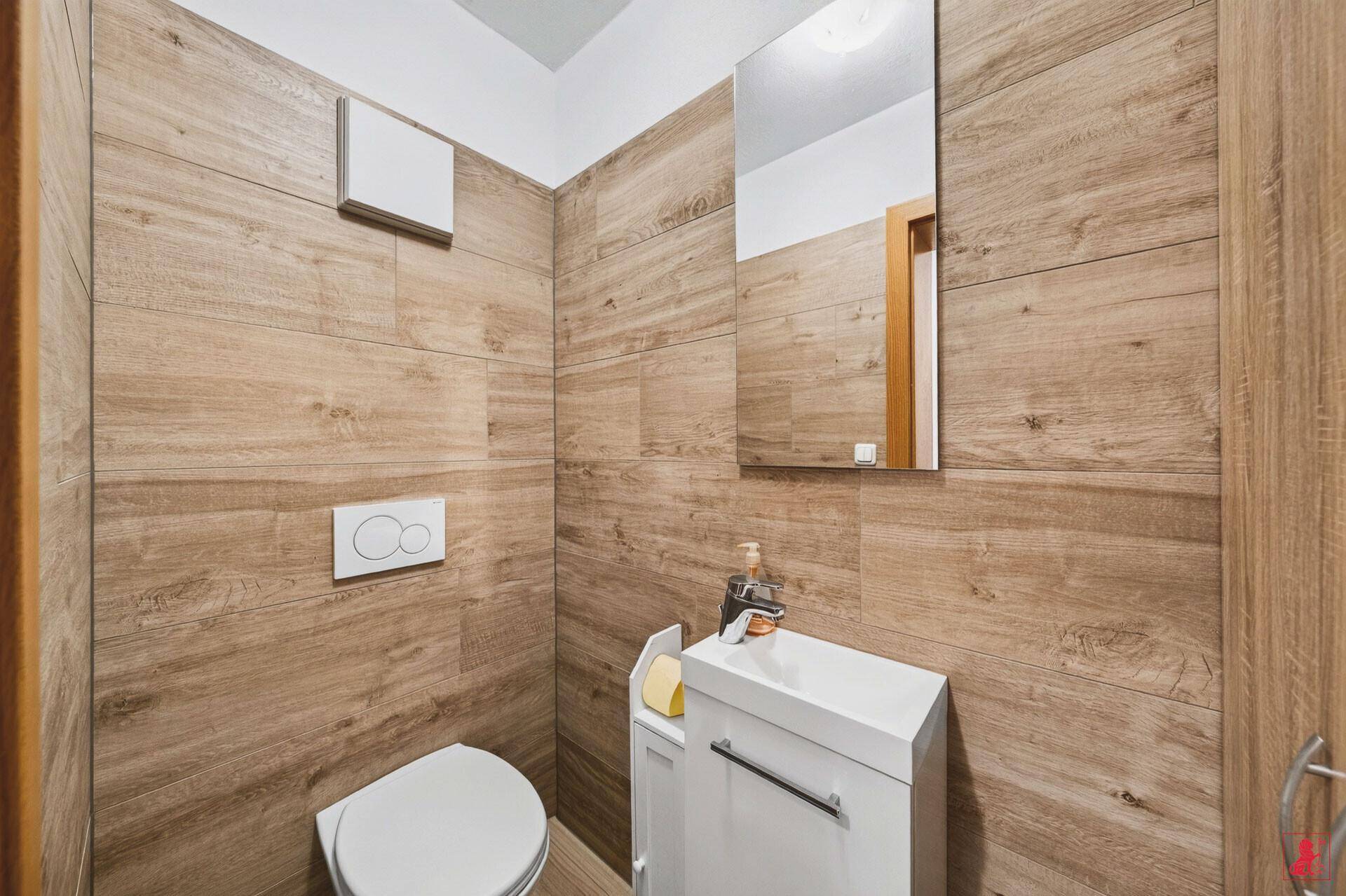 Modernes Gäste-WC mit Holzoptik-Fliesen, wandhängendem WC und kleinem Waschbecken.