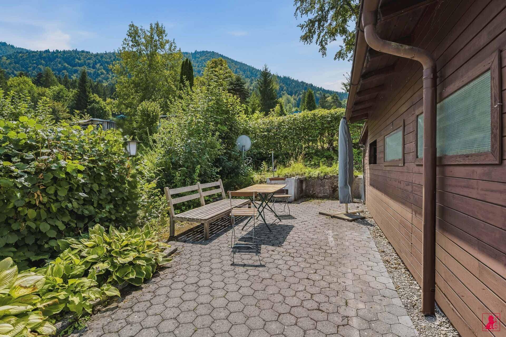 Gepflasterte Terrasse mit Holzbänken und Blick ins Grüne.