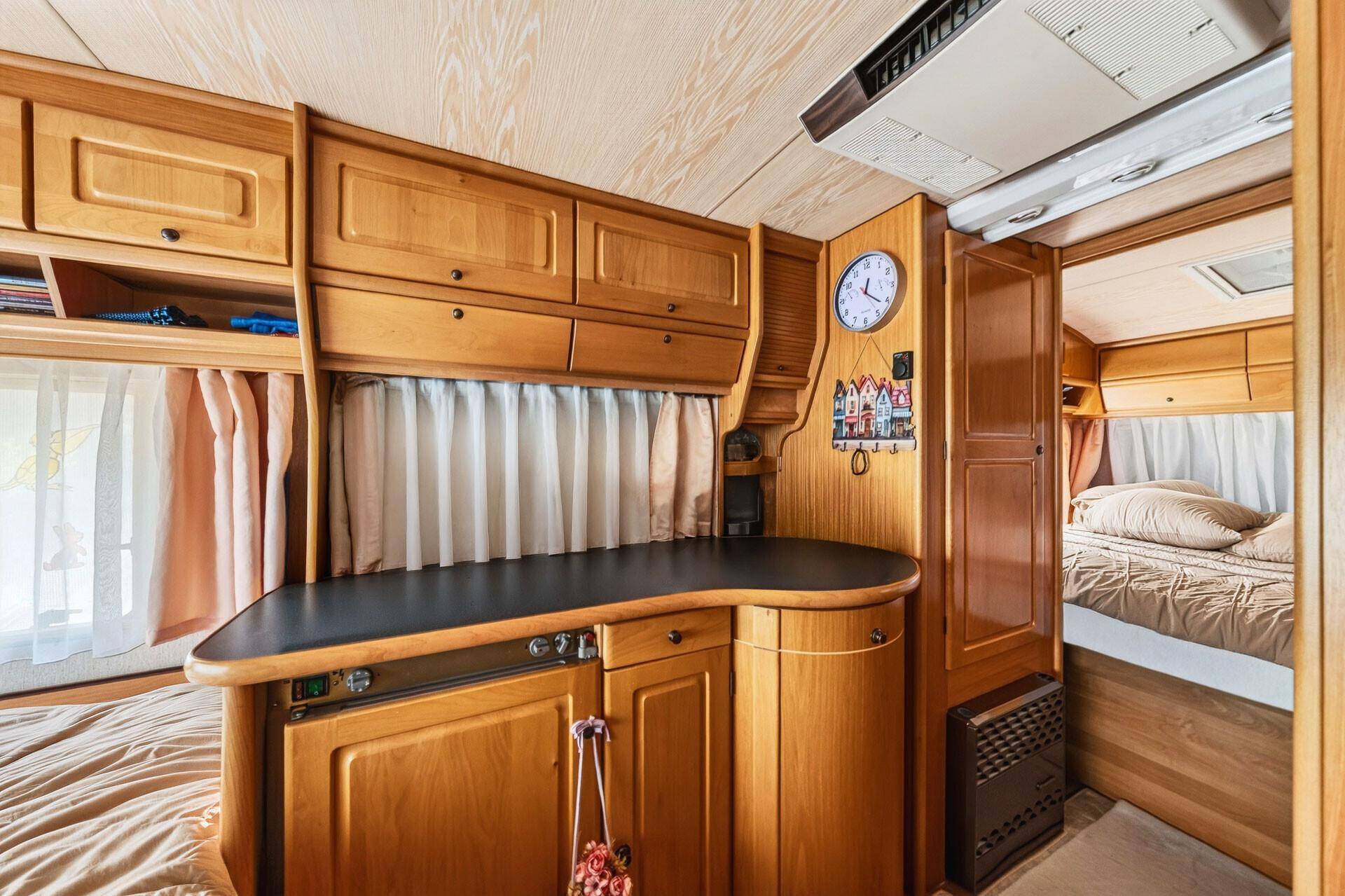 Kleine Küchenzeile im Wohnwagen mit Arbeitsfläche und Holzschränken, integriert in den Raum.