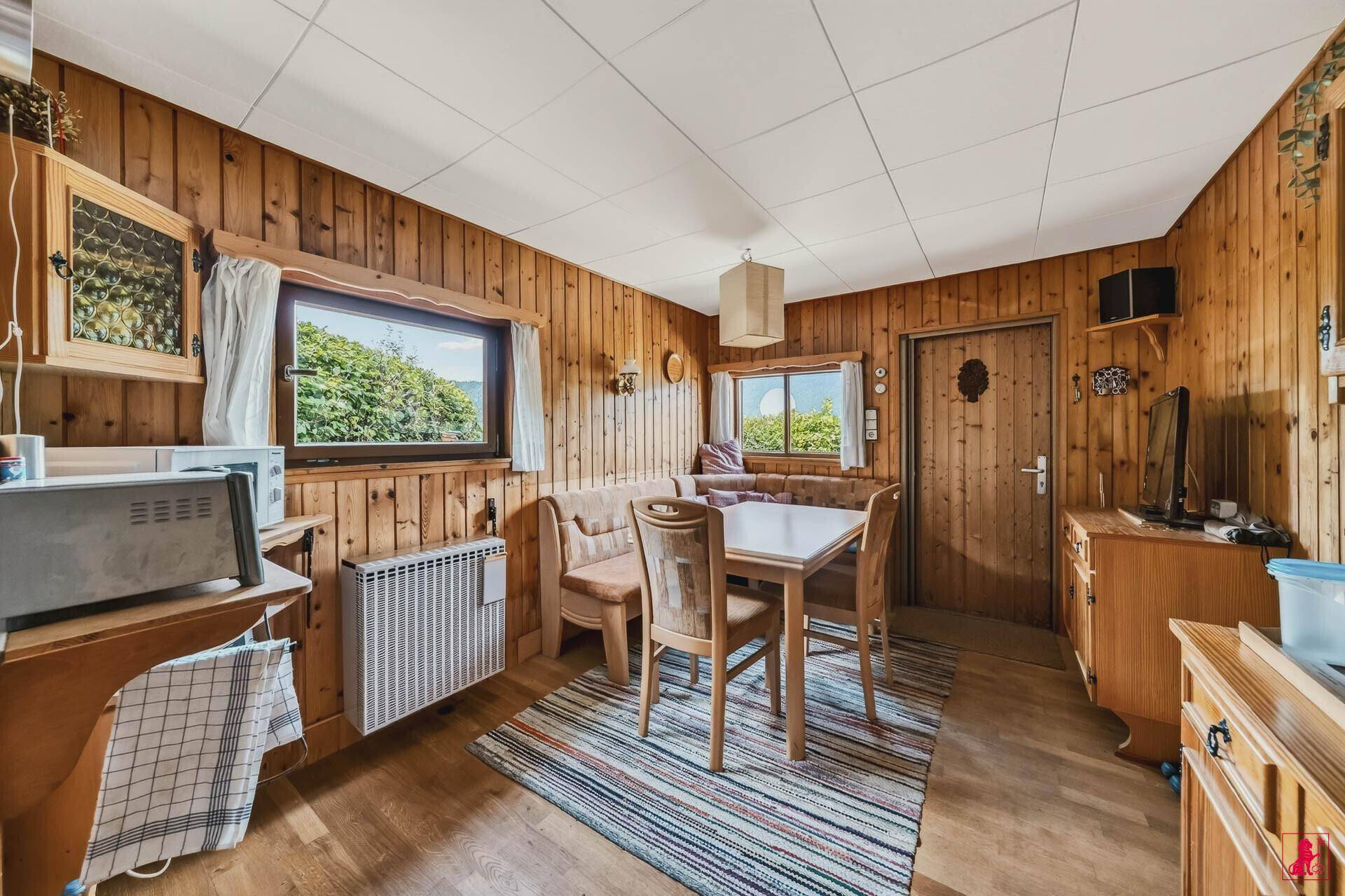 Gemütlicher Wohn-Essbereich mit Holzvertäfelung, Esstisch und Sitzbank.