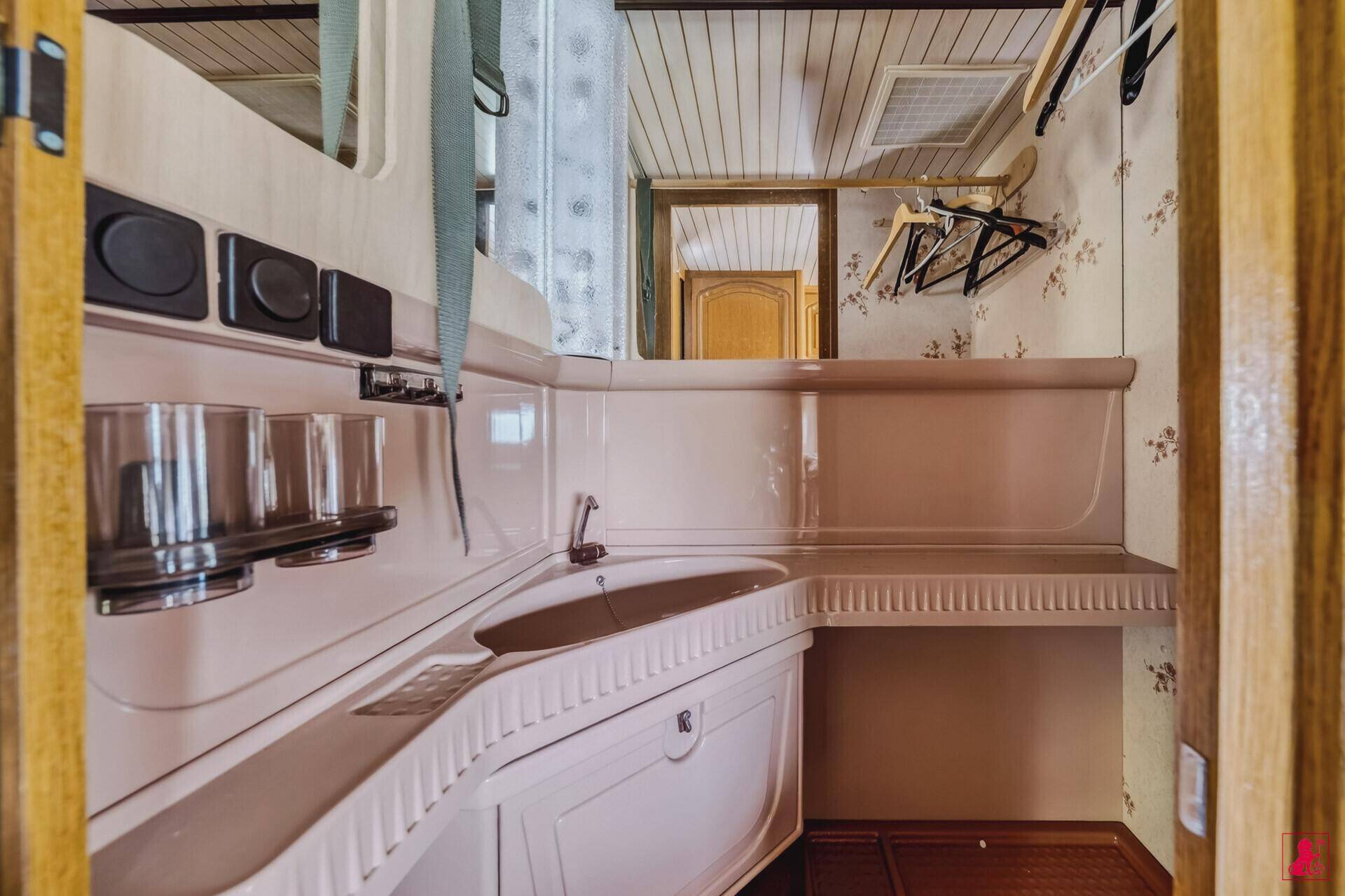 Kleines Badezimmer mit Waschbecken und Ablageflächen in einem Wohnwagen.