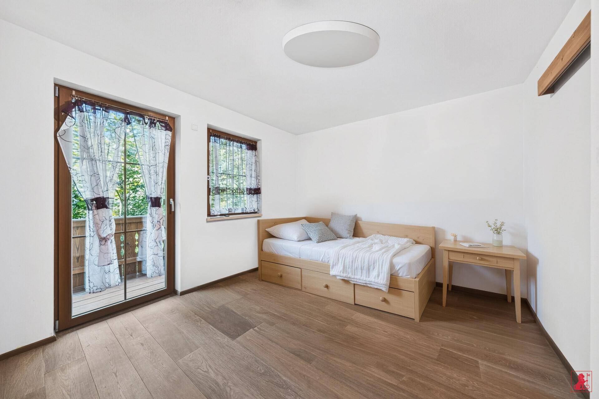 Schlafzimmer mit Einzelbett, Holzboden und direktem Zugang zu einem Balkon.