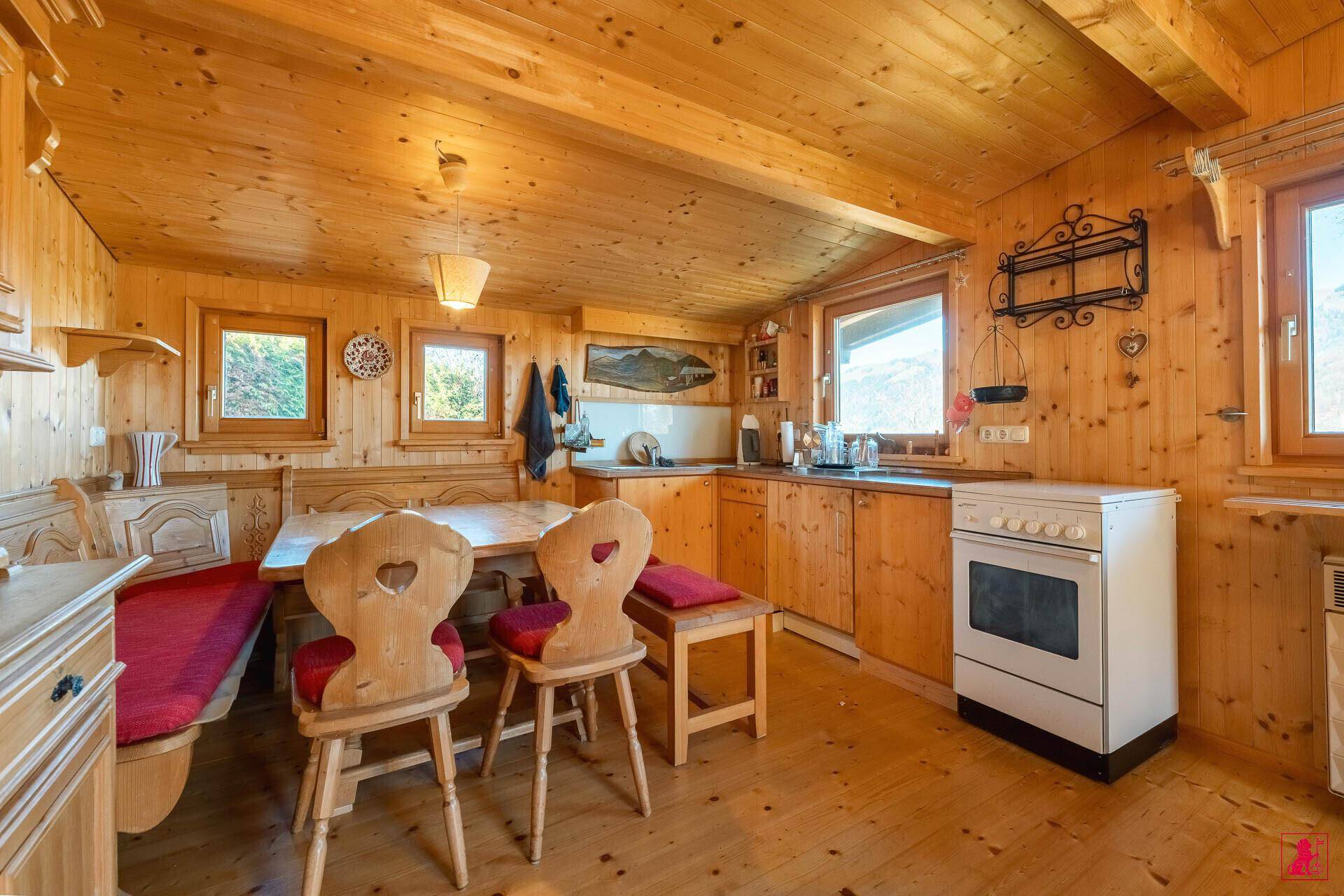 Traditionelle Wohnküche mit Holztisch, Eckbank und Blick auf die umliegende Landschaft.