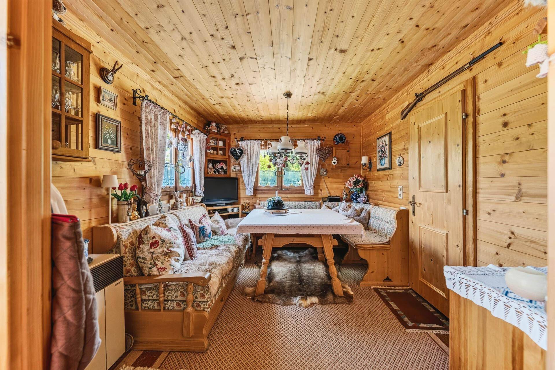 Traditioneller Wohn-Essbereich im alpinen Stil mit Holzwänden und gemütlicher Sitzecke.
