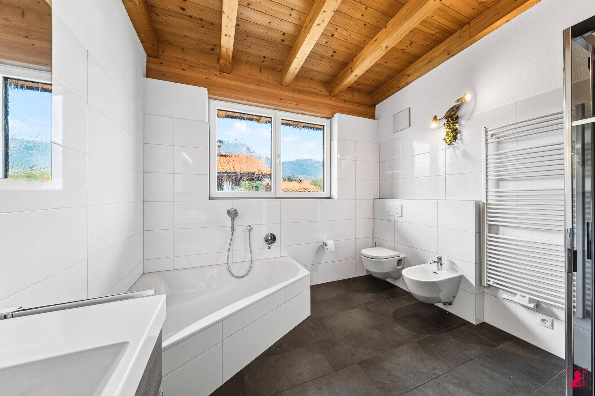 Helles Badezimmer mit Badewanne, WC, Bidet und beheiztem Handtuchhalter.