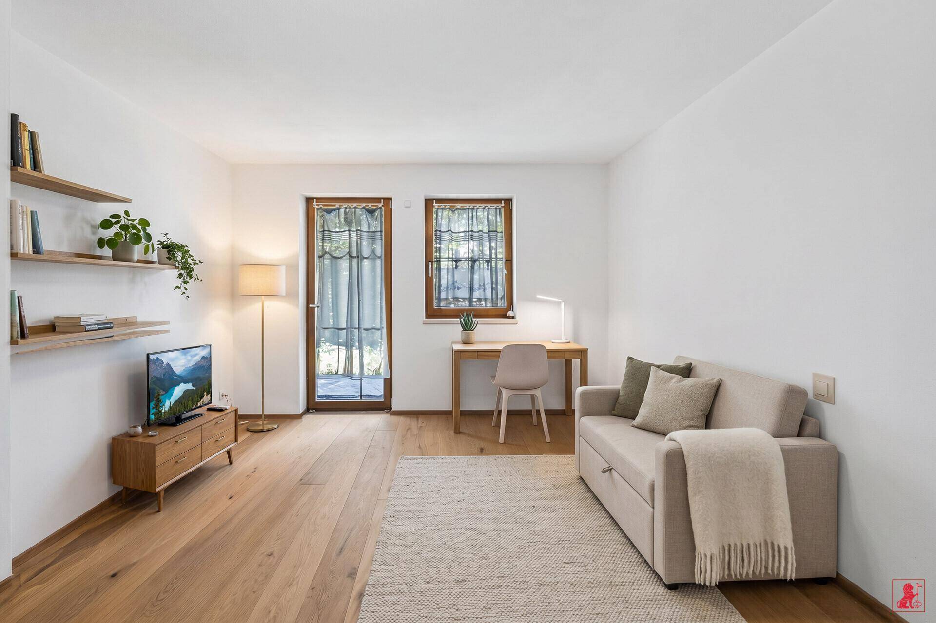 Heller Wohnraum mit Schlafsofa, Schreibtisch und Holzboden, ideal als Gästezimmer oder Büro.