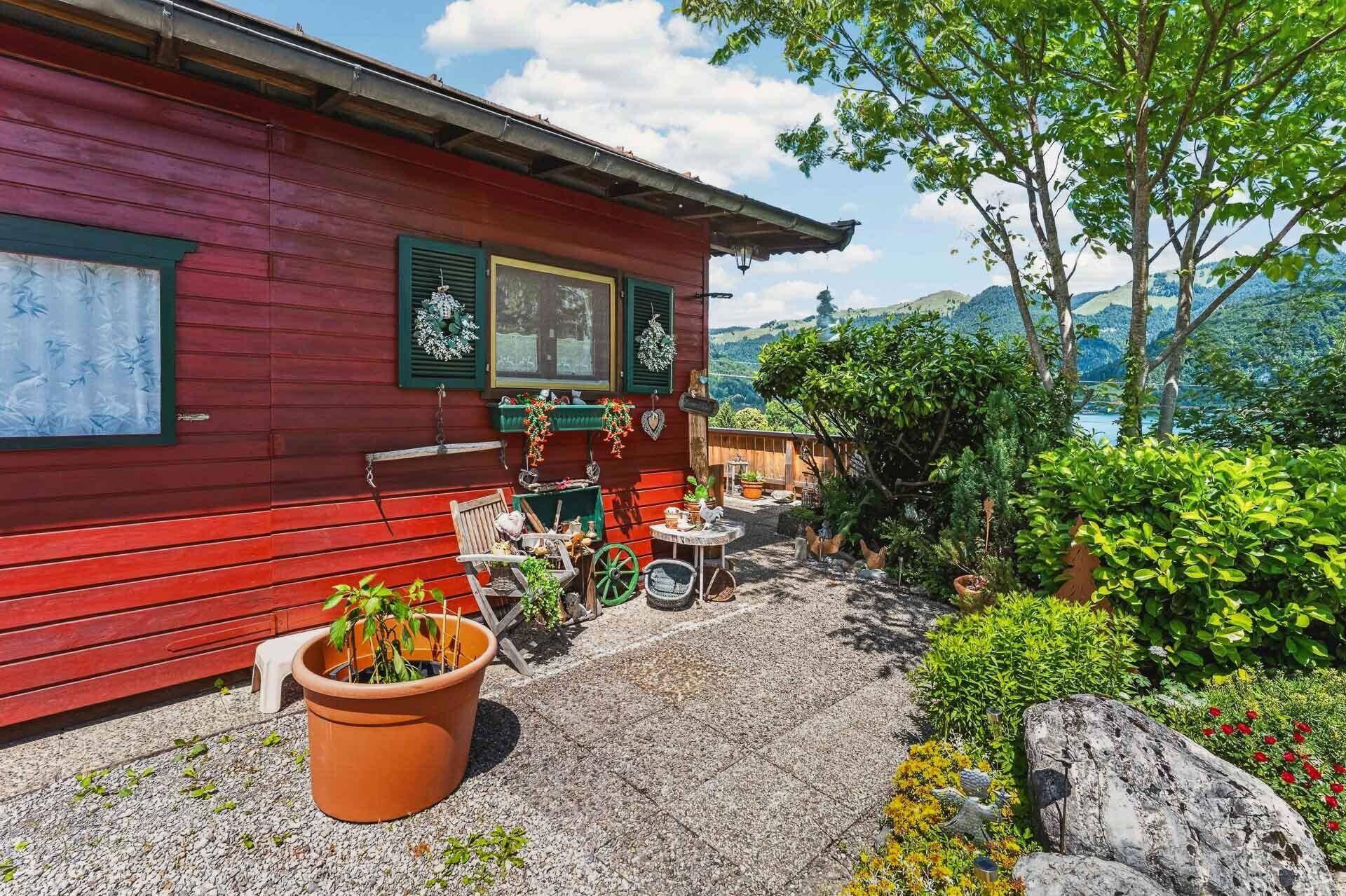 Gemütlicher Außenbereich mit kleiner Terrasse und traditioneller Dekoration am roten Holzhaus.