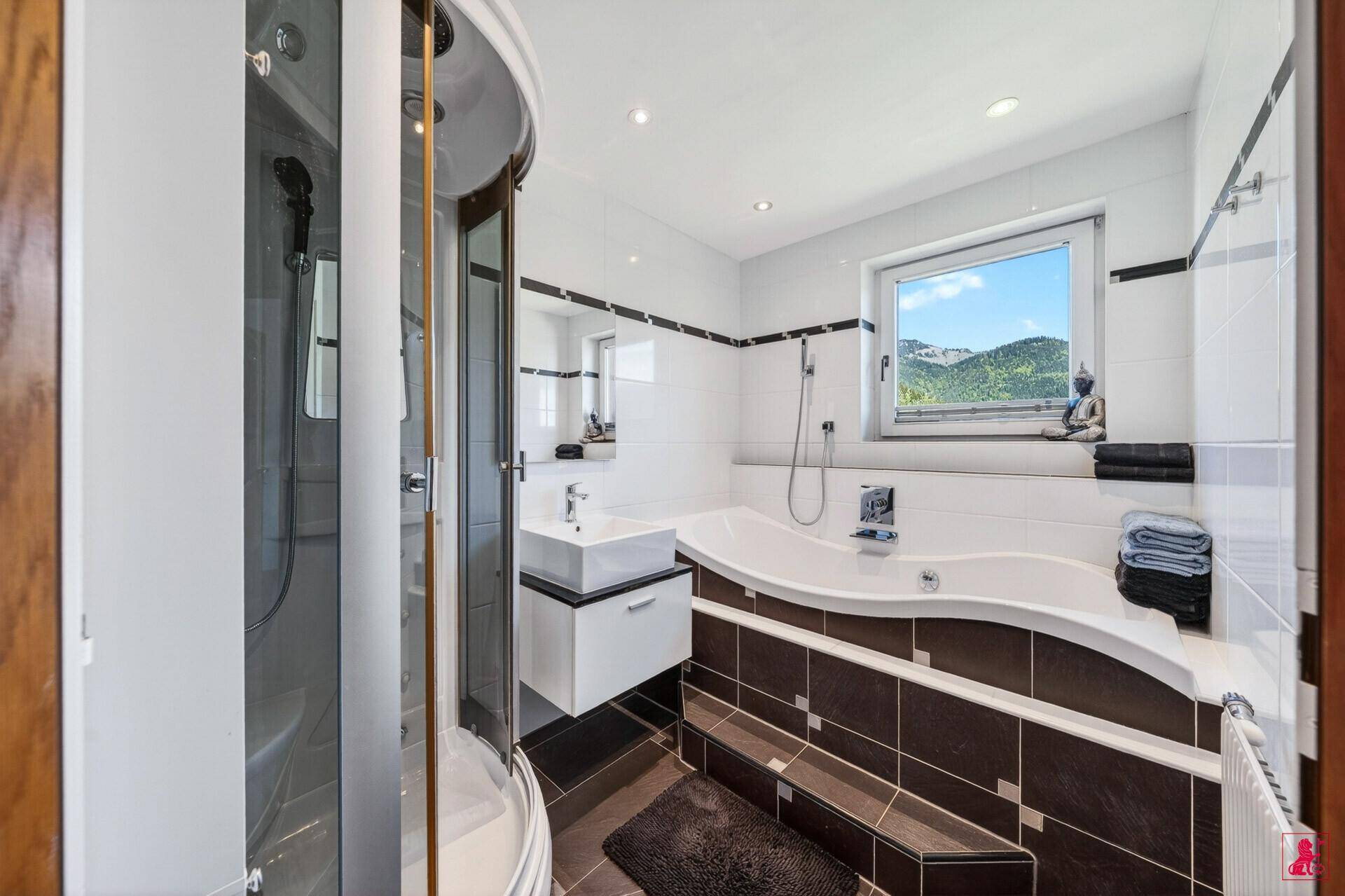 Modernes Badezimmer mit Badewanne, Duschkabine und Fenster mit Bergblick.