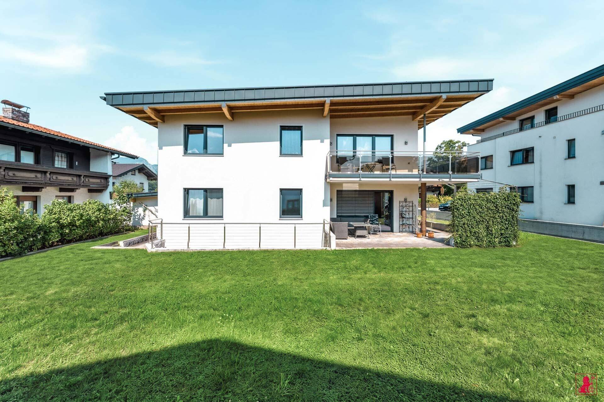Rückansicht des modernen Hauses mit gepflegtem Rasen und großem Balkon.