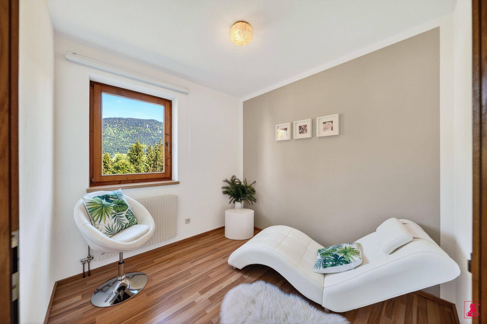 Kleines Zimmer mit Laminatboden, Liege und Fenster mit Bergblick.