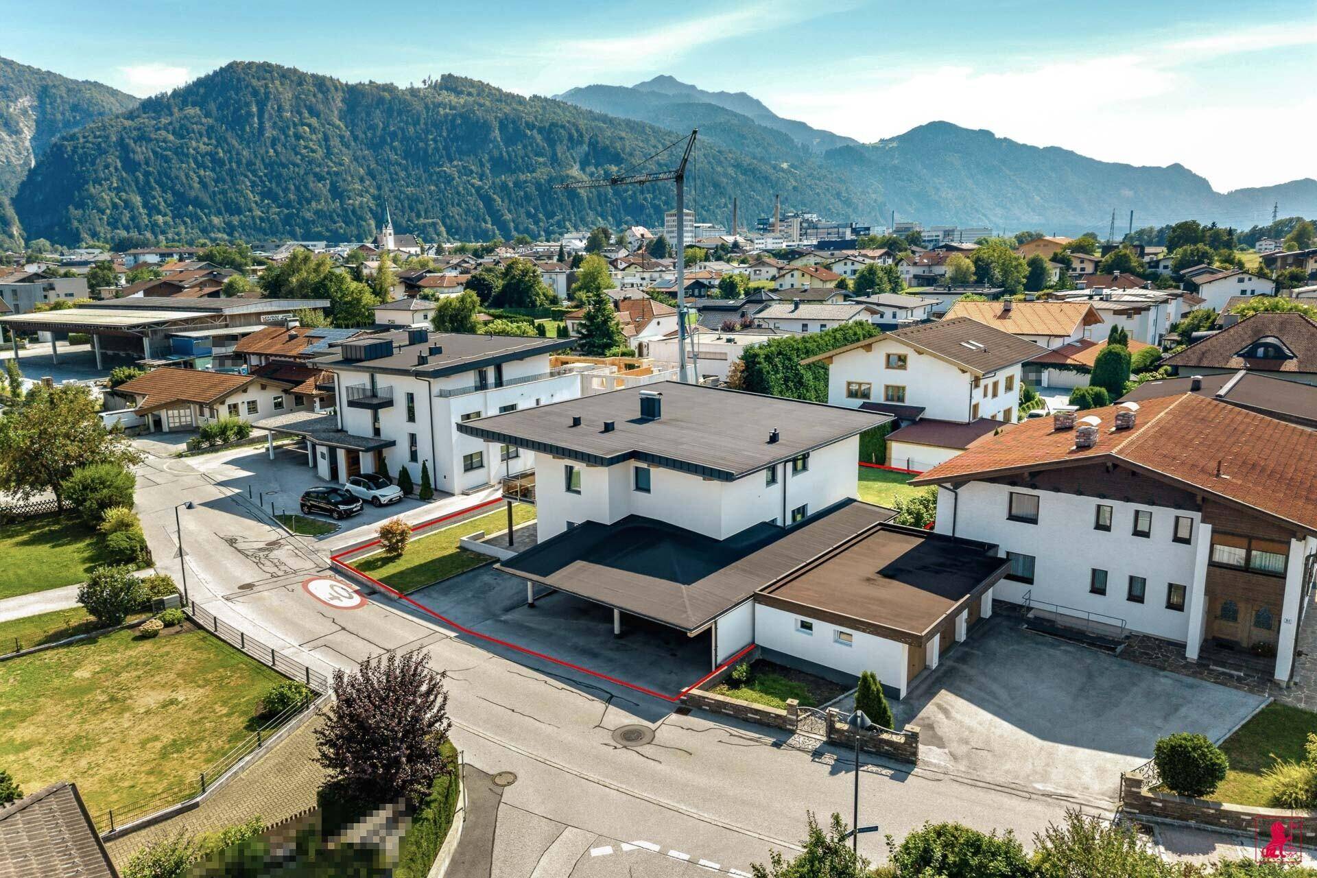 Luftaufnahme des Anwesens mit umliegender Bebauung und Bergpanorama im Hintergrund.