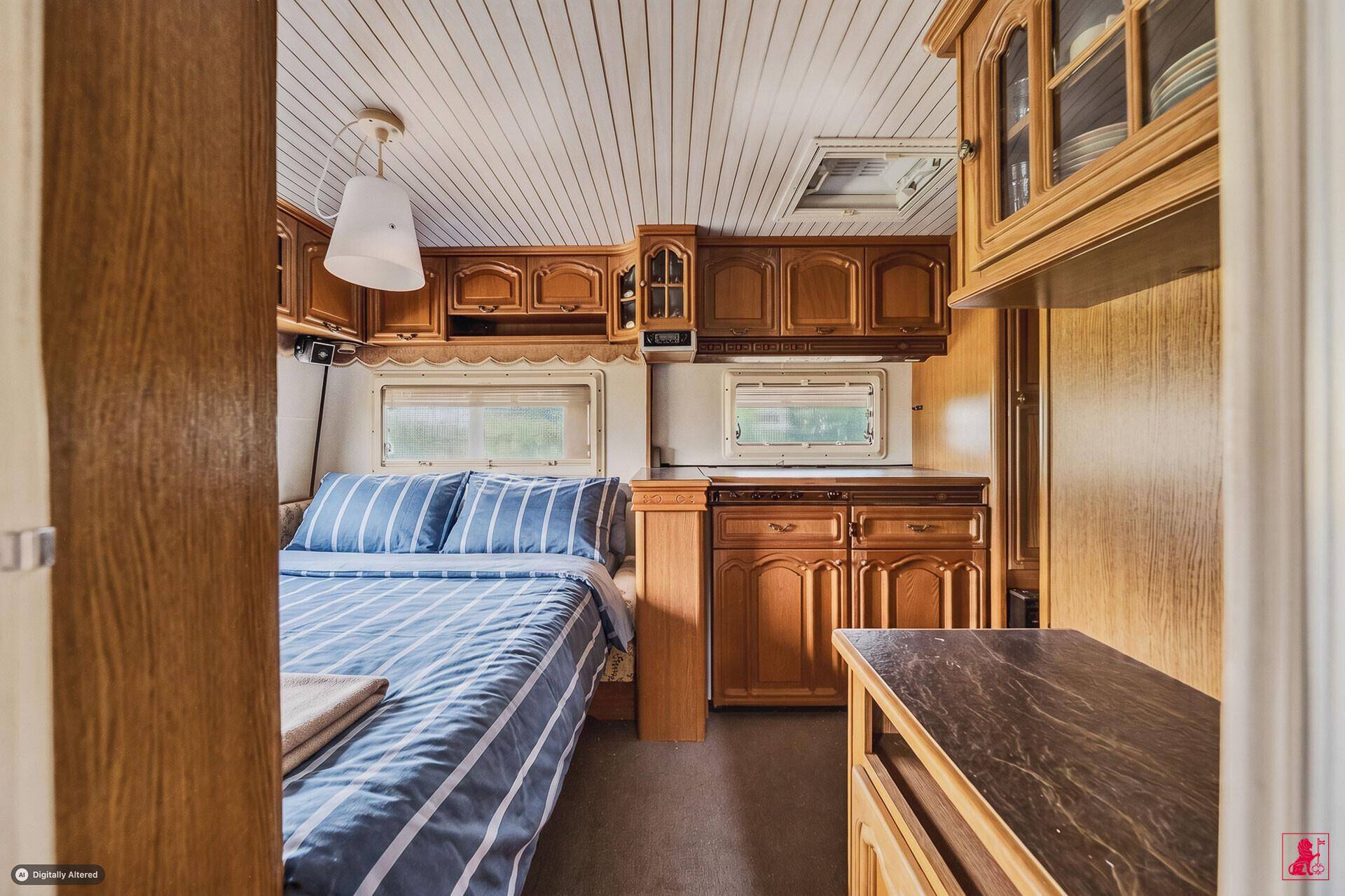 Gemütliches Schlafzimmer in einem Wohnwagen mit Doppelbett und Holzschränken.