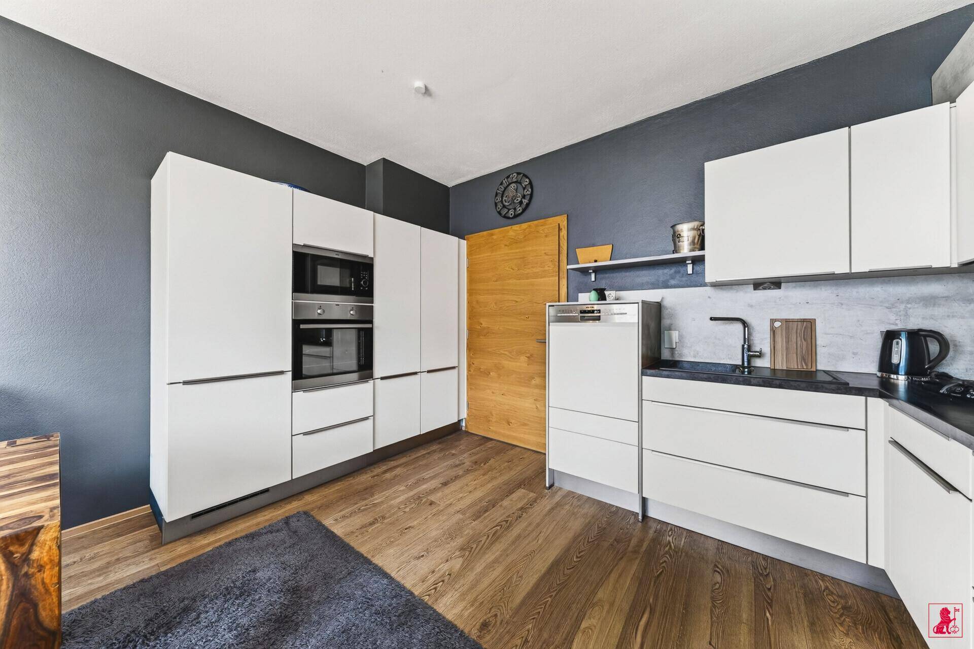 Moderne Küche mit weißen Fronten, integrierten Geräten und Holzboden.