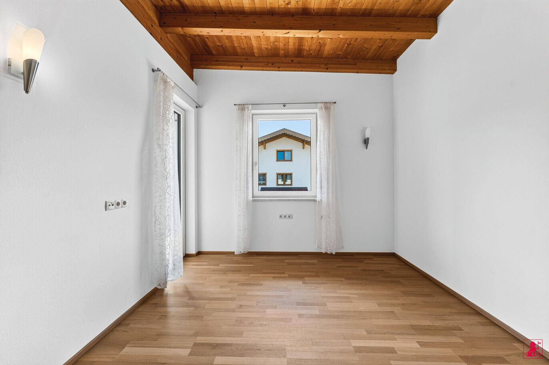 Helles Schlafzimmer mit Holzbalkendecke, Parkettboden und Zugang zu einem französischen Balkon.
