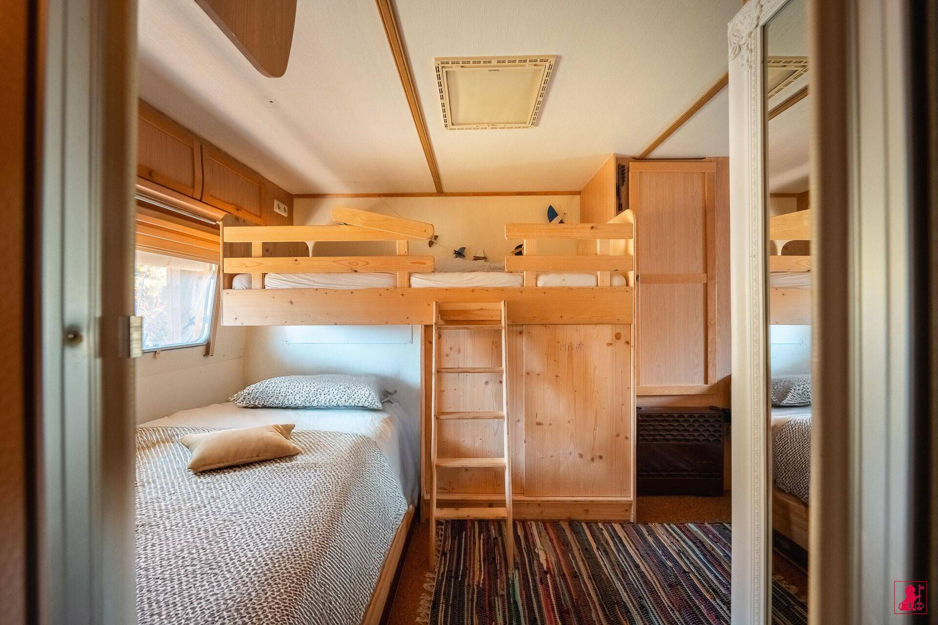 Kinderzimmer mit Etagenbetten, Einzelbett und rustikalem Holzinterieur.