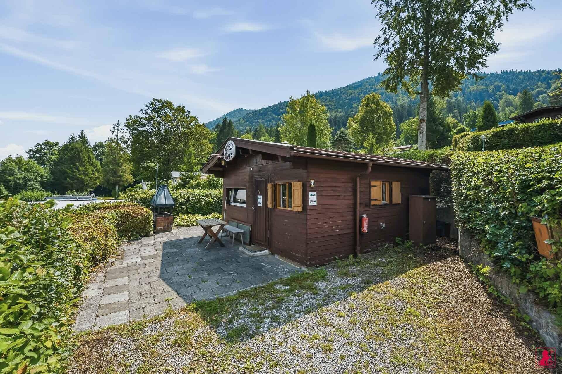 Kleines Holzhaus in ländlicher Umgebung mit gepflastertem Vorplatz und Garten.
