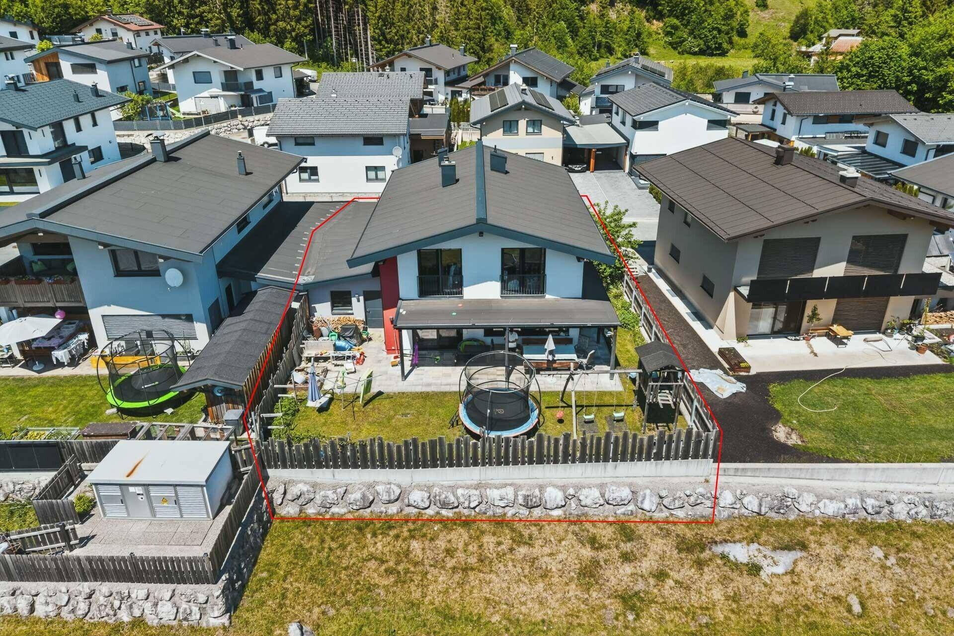 Luftaufnahme eines Einfamilienhauses mit Garten, Trampolin und umzäuntem Grundstück in Wohnsiedlung.