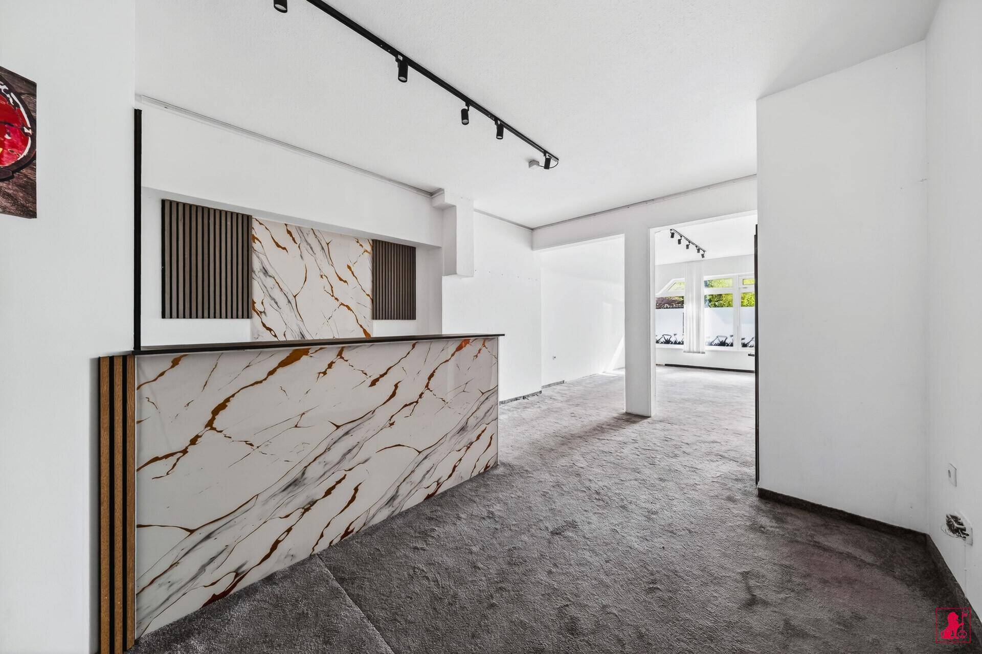 Moderner Empfangsbereich mit eleganter Theke in Marmoroptik und dekorativer Holzlamellenwand.