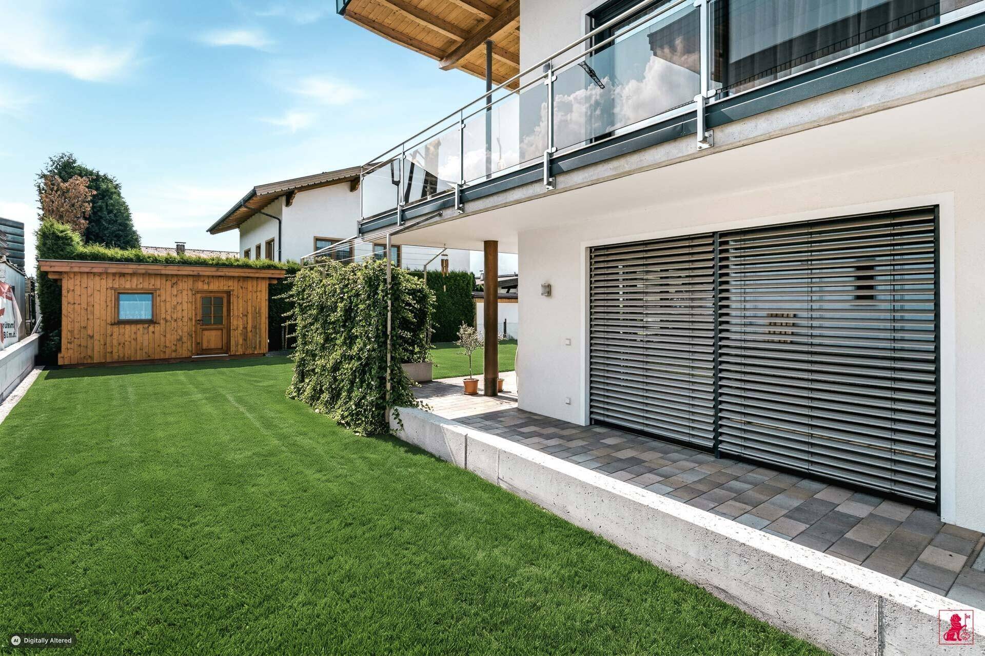 Gepflegter Gartenbereich mit Rasenfläche, Hecke und einem Holzgartenhaus.