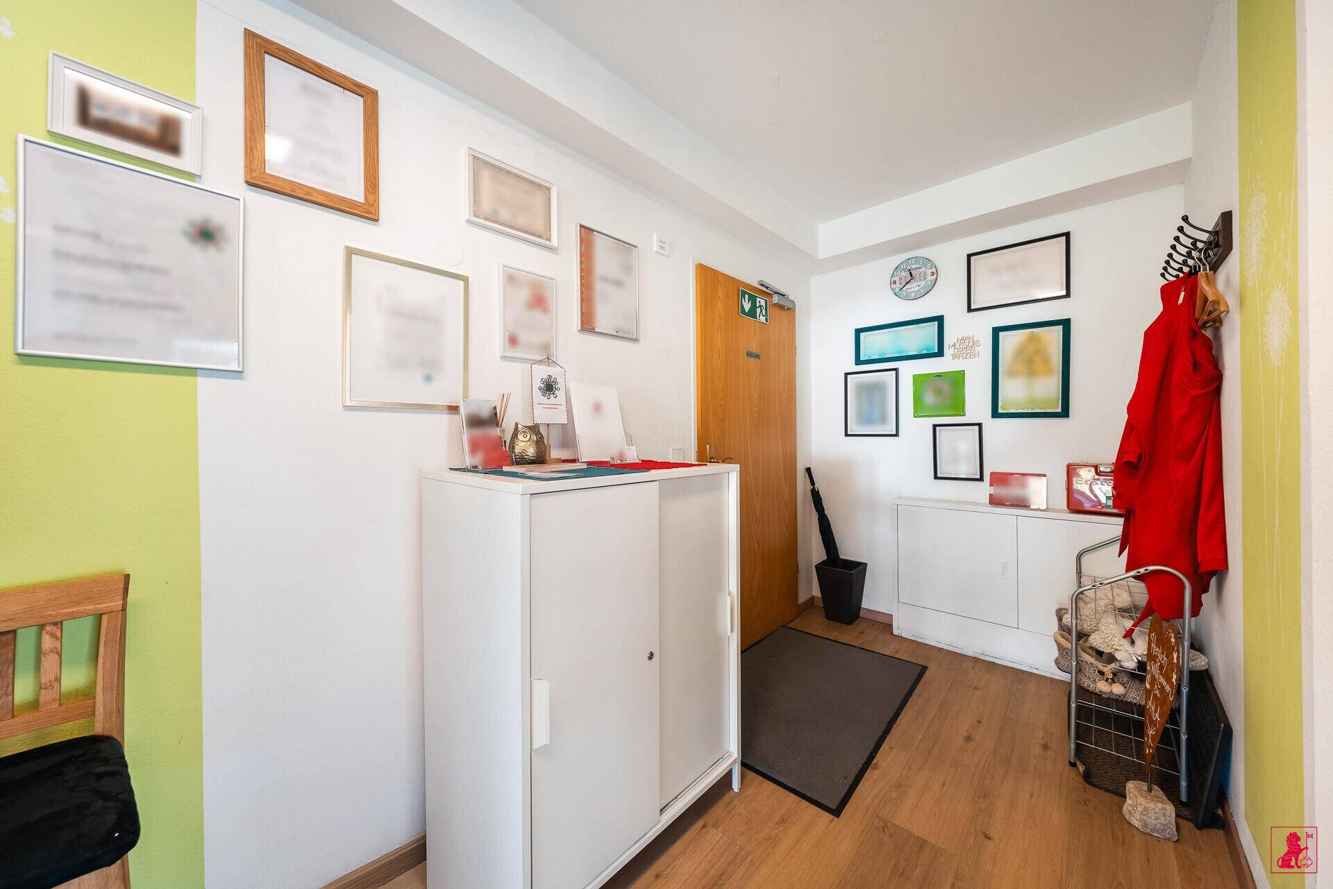 Eingangsbereich mit weißem Schrank, Garderobe und gerahmten Bildern an der Wand.