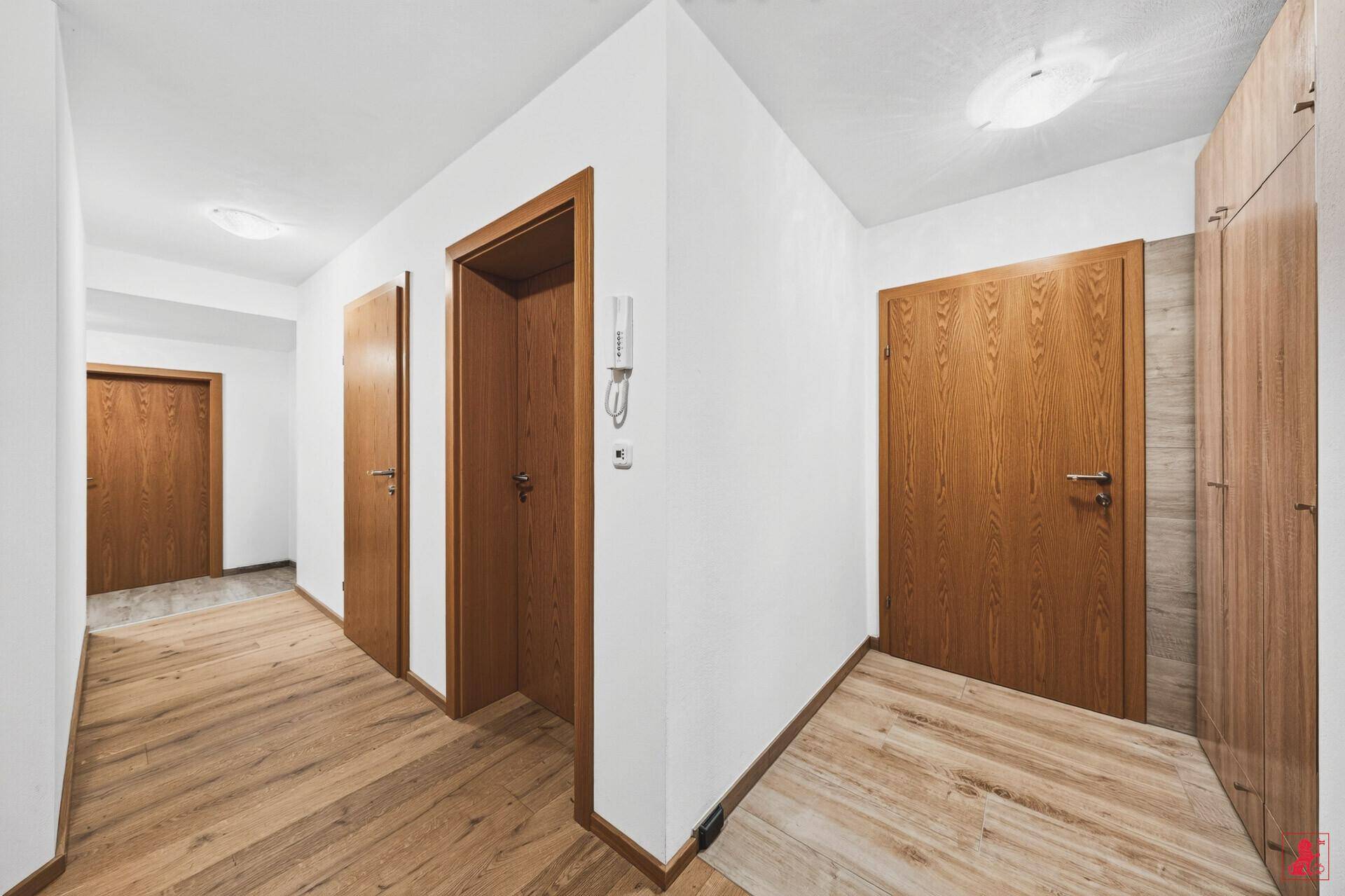 Heller Flur mit Holztüren und Holzboden, der zu weiteren Räumen führt.