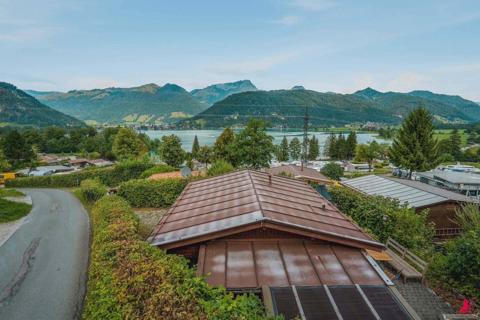 Dach des Holzhauses mit Solarpaneelen und weitem Blick auf den See und die Berge.