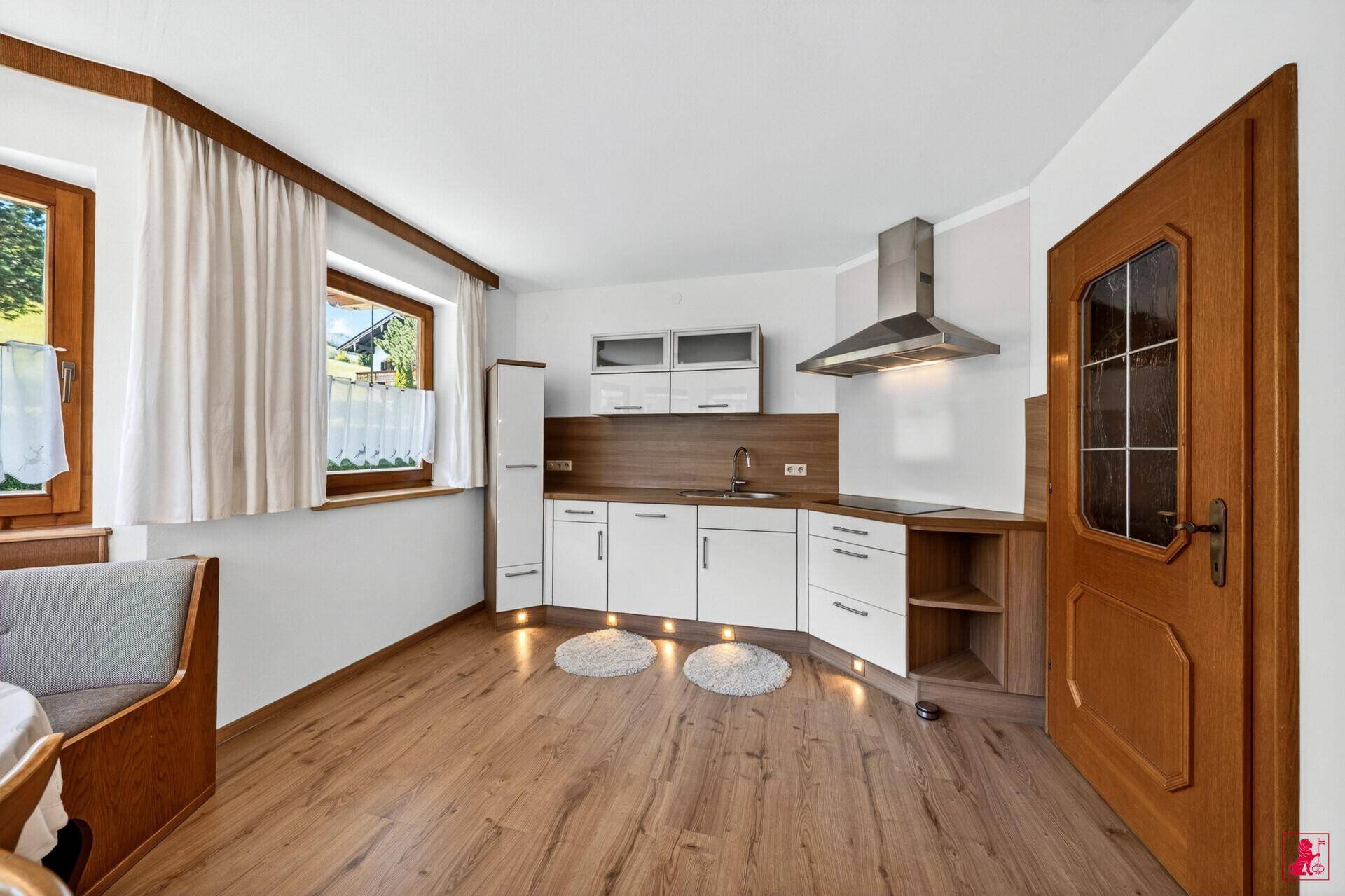 Helle Küche mit Laminatboden, weißen Schränken und integriertem Essbereich.
