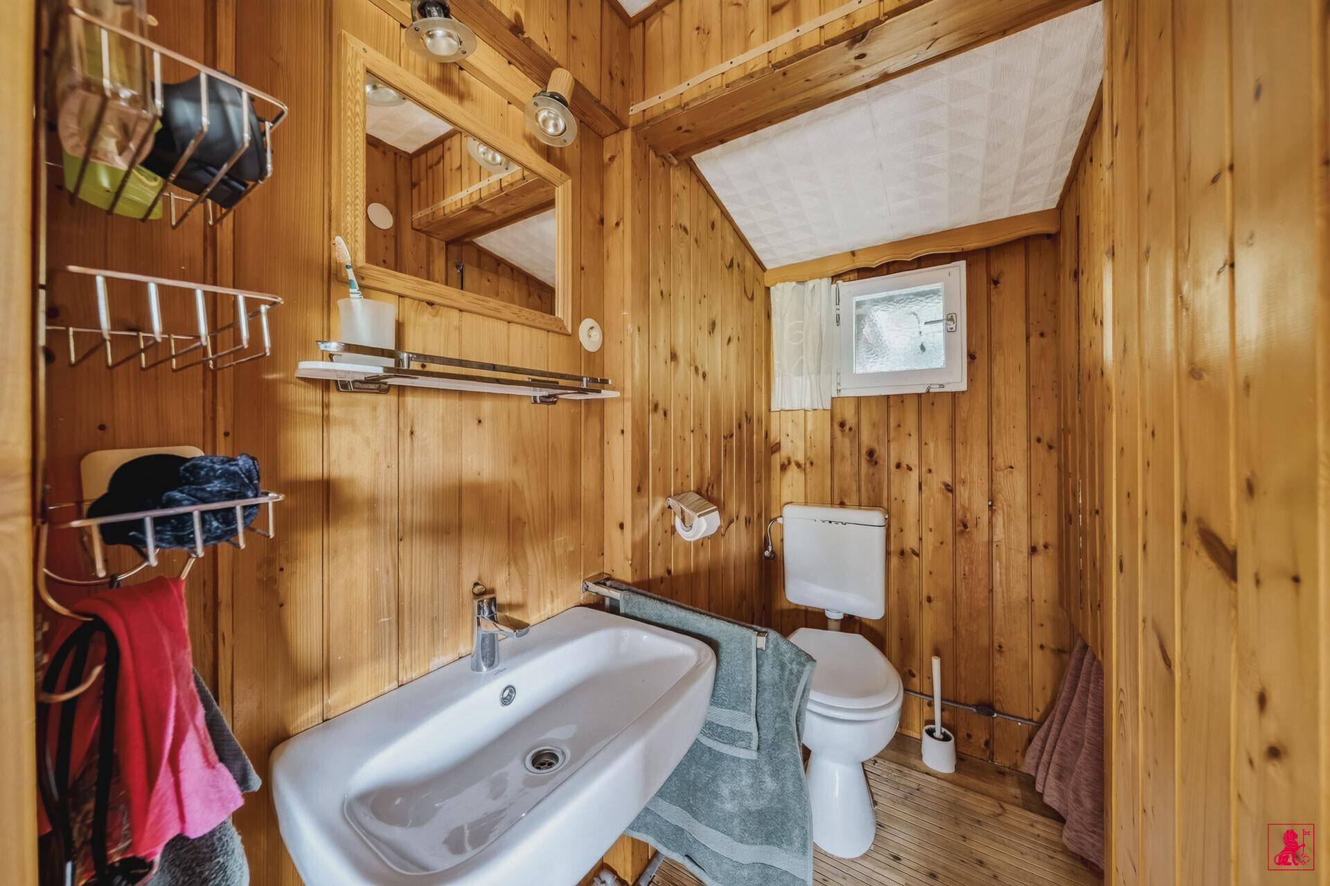 Kleines Badezimmer mit Holzvertäfelung, Waschbecken und Toilette.