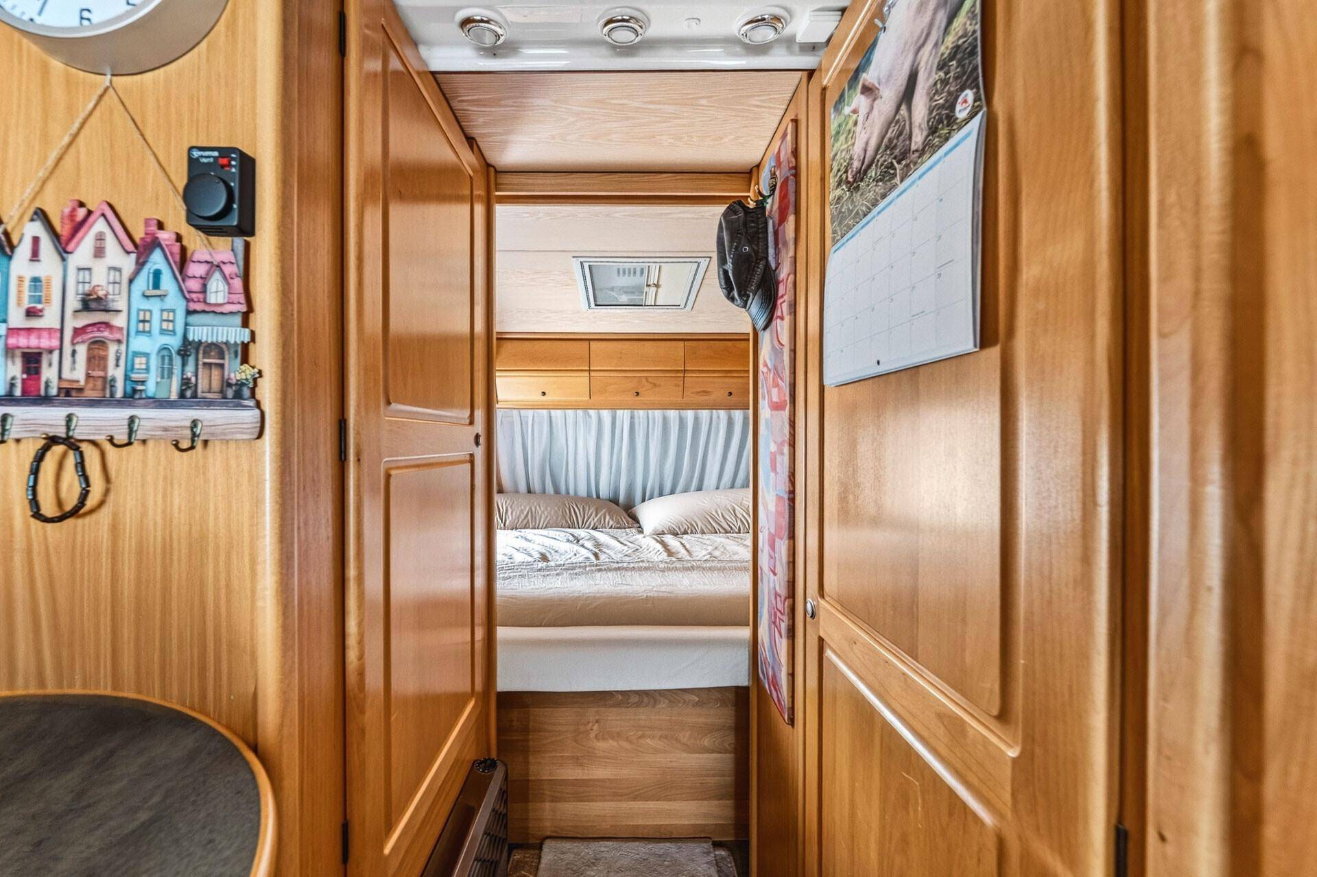 Schmaler Durchgang im Wohnwagen, der zu einem weiteren Schlafbereich führt, mit Holzwänden.