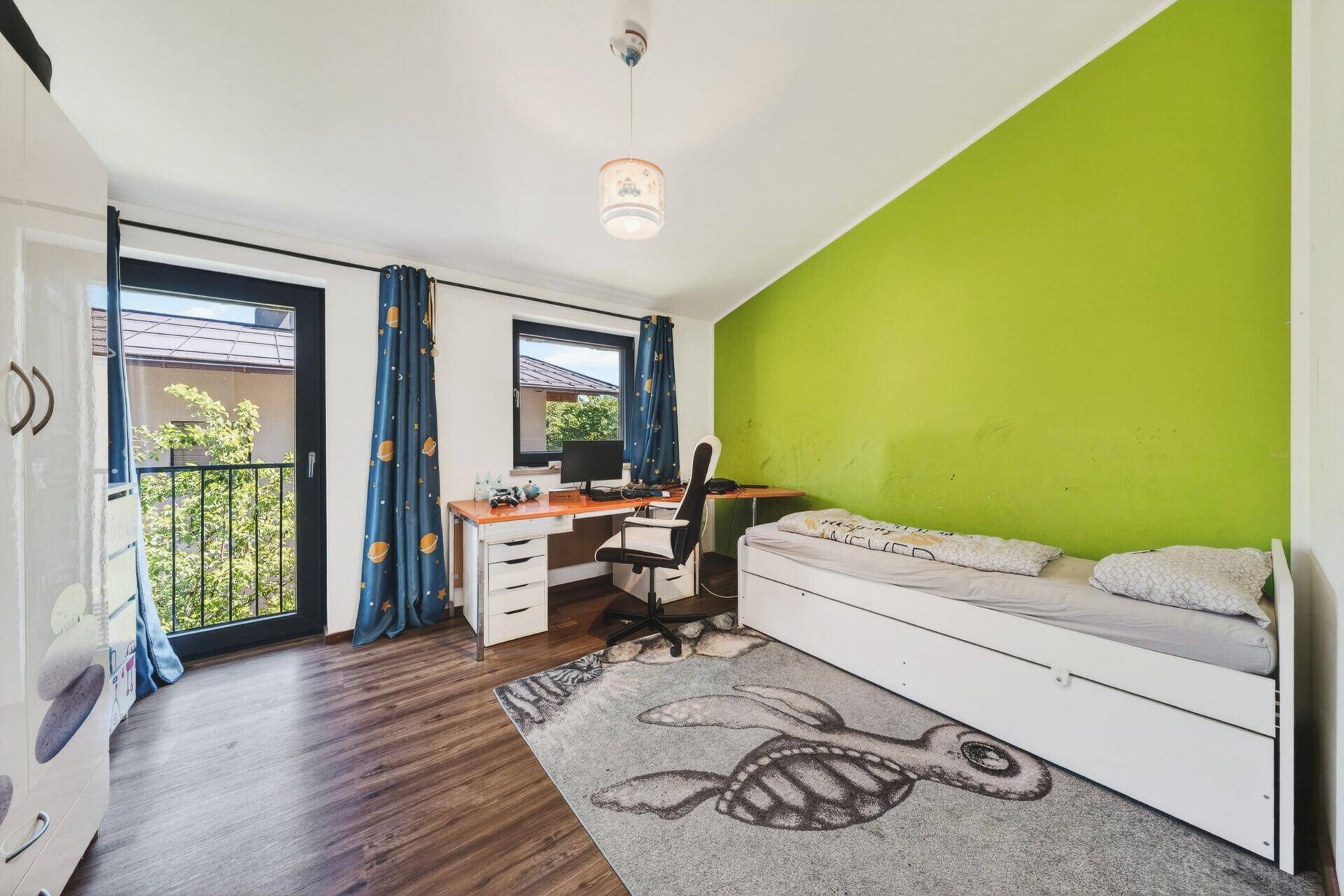 Helles Kinderzimmer mit Schreibtisch, Einzelbett und einer auffälligen grünen Akzentwand.