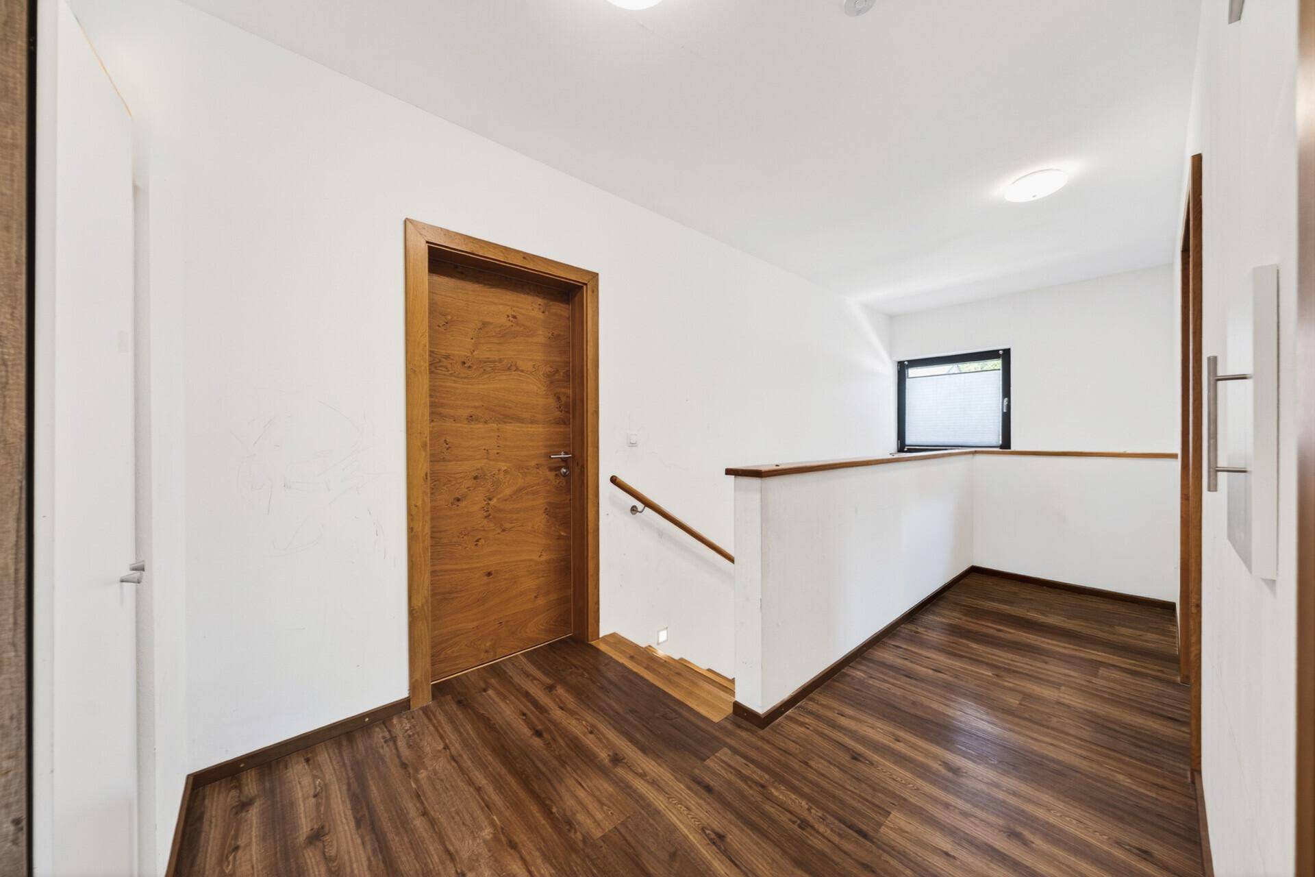 Heller Flur im Obergeschoss mit Holzfußboden und einer Treppe, die nach unten führt.